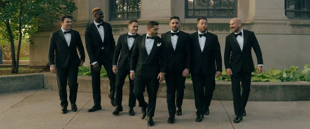 A group of groomsmen walking together in black suits.