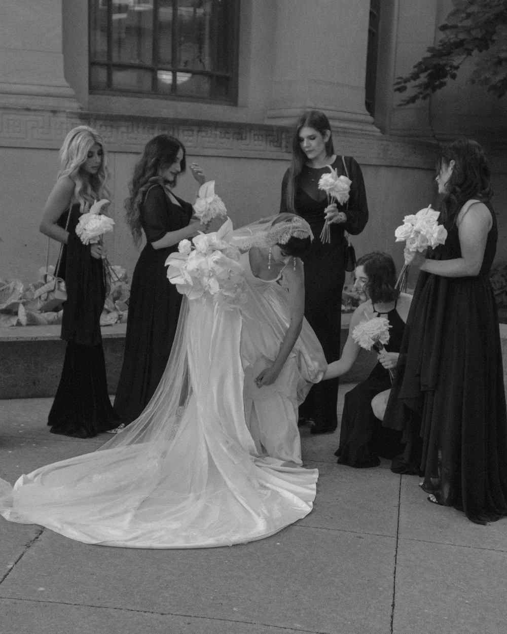 Black-and-white photograph of a bride surrounded by attendants.