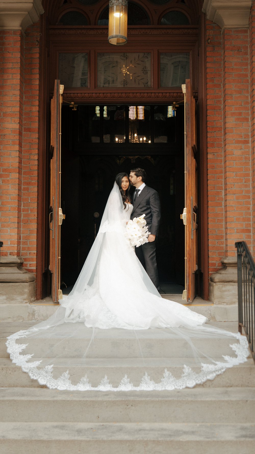 A long white wedding train framed by a tall wooden doorway.
