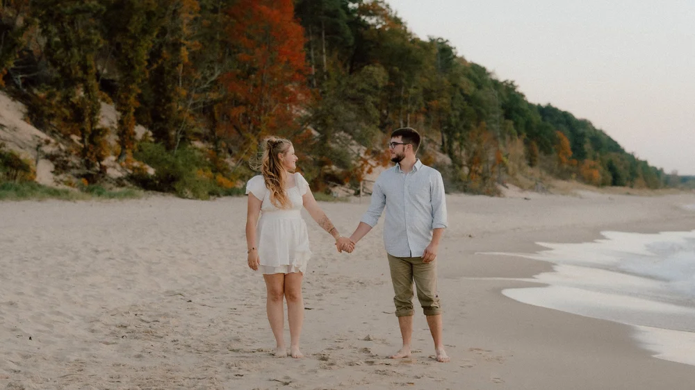 A couple walking barefoot along the shoreline.