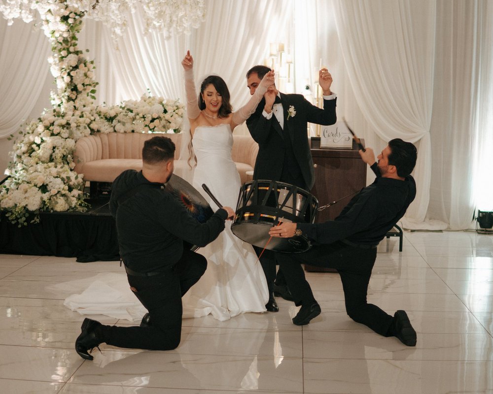 Wedding guests celebrating with a couple beneath white draping.