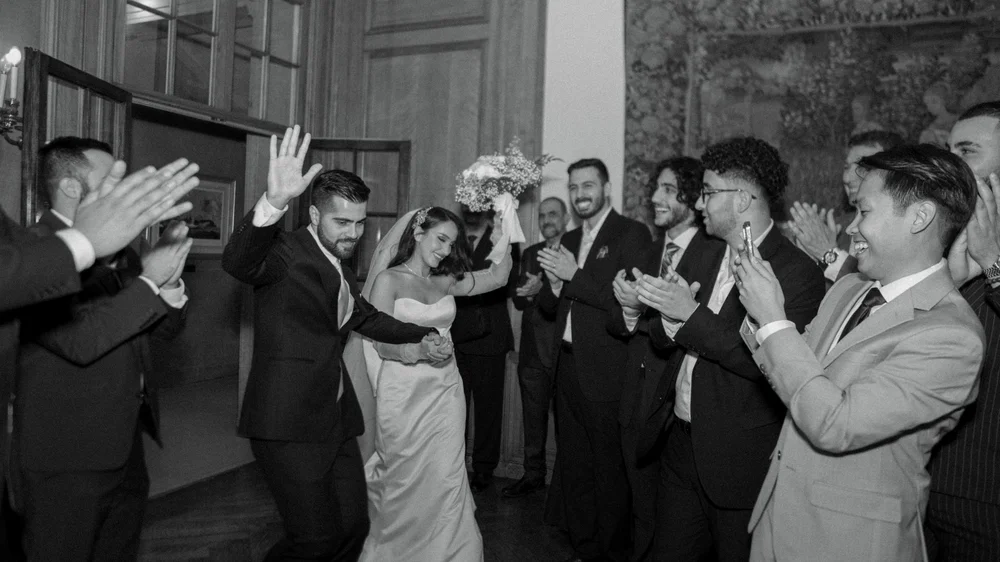 Black-and-white photograph of a group raising glasses in a toast.