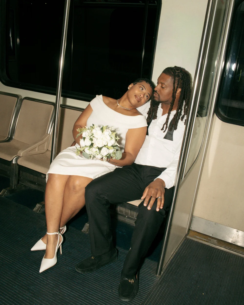 A couple sharing a kiss while seated in a train doorway.
