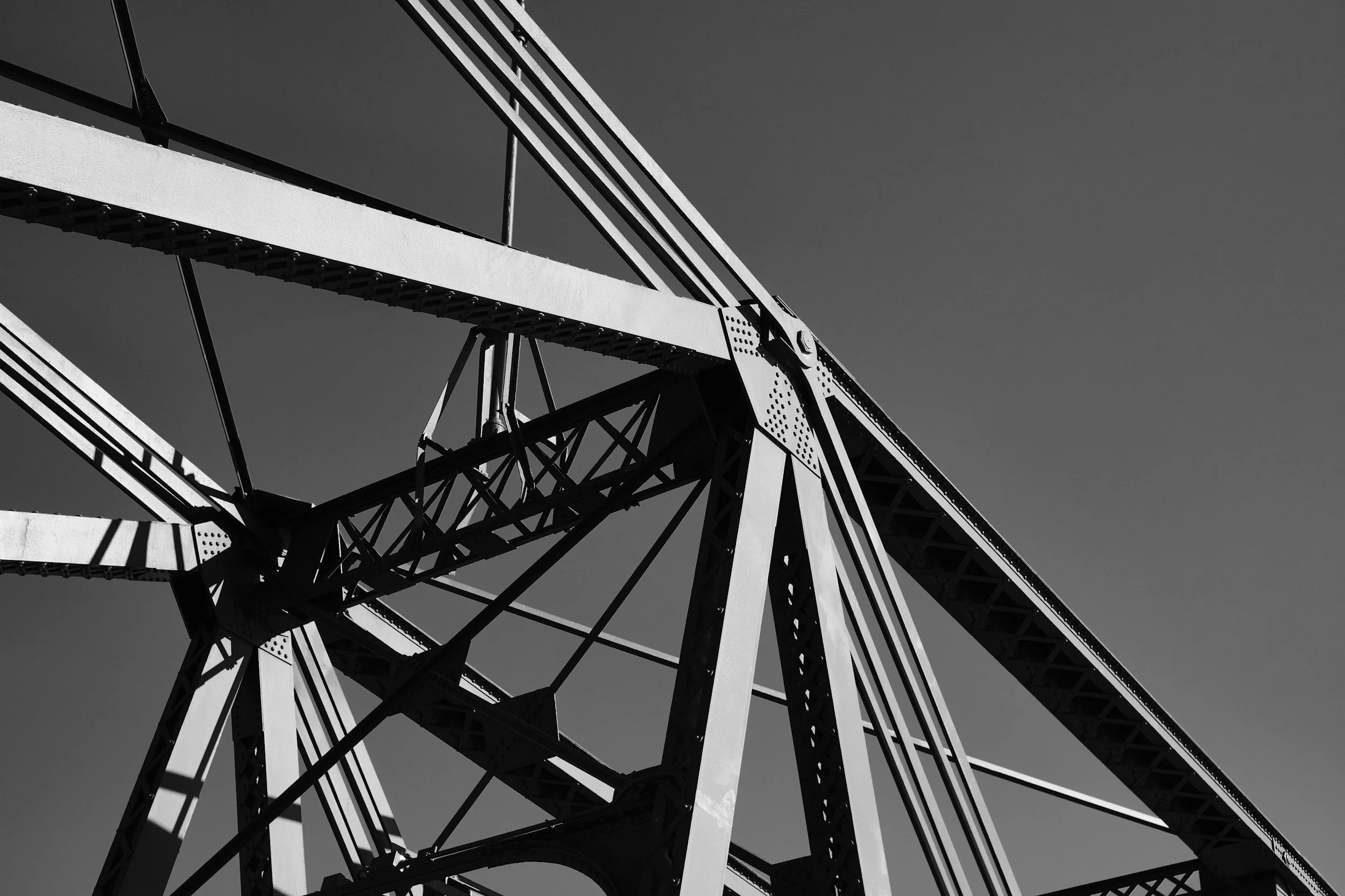 Black and white photo of a Ferris wheel taken from below against a clear sky.