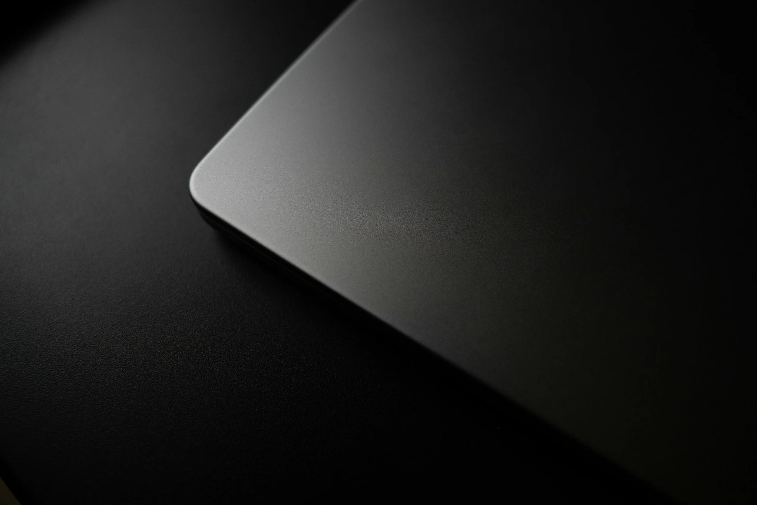 Close-up of a sleek, modern gray laptop with rounded edges on a dark textured surface.