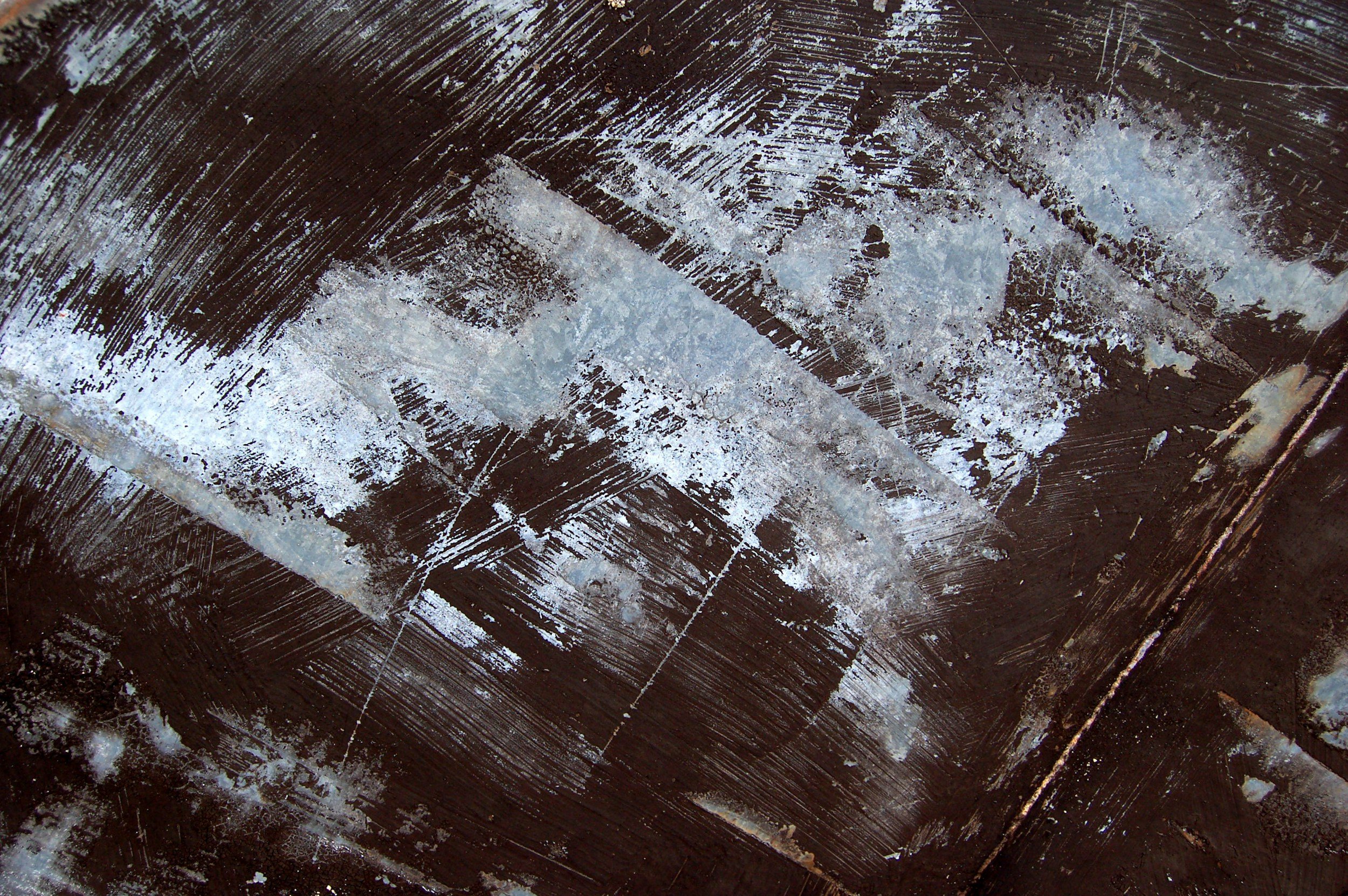 Close-up of a wooden surface with white chalk or paint markings and scratches.