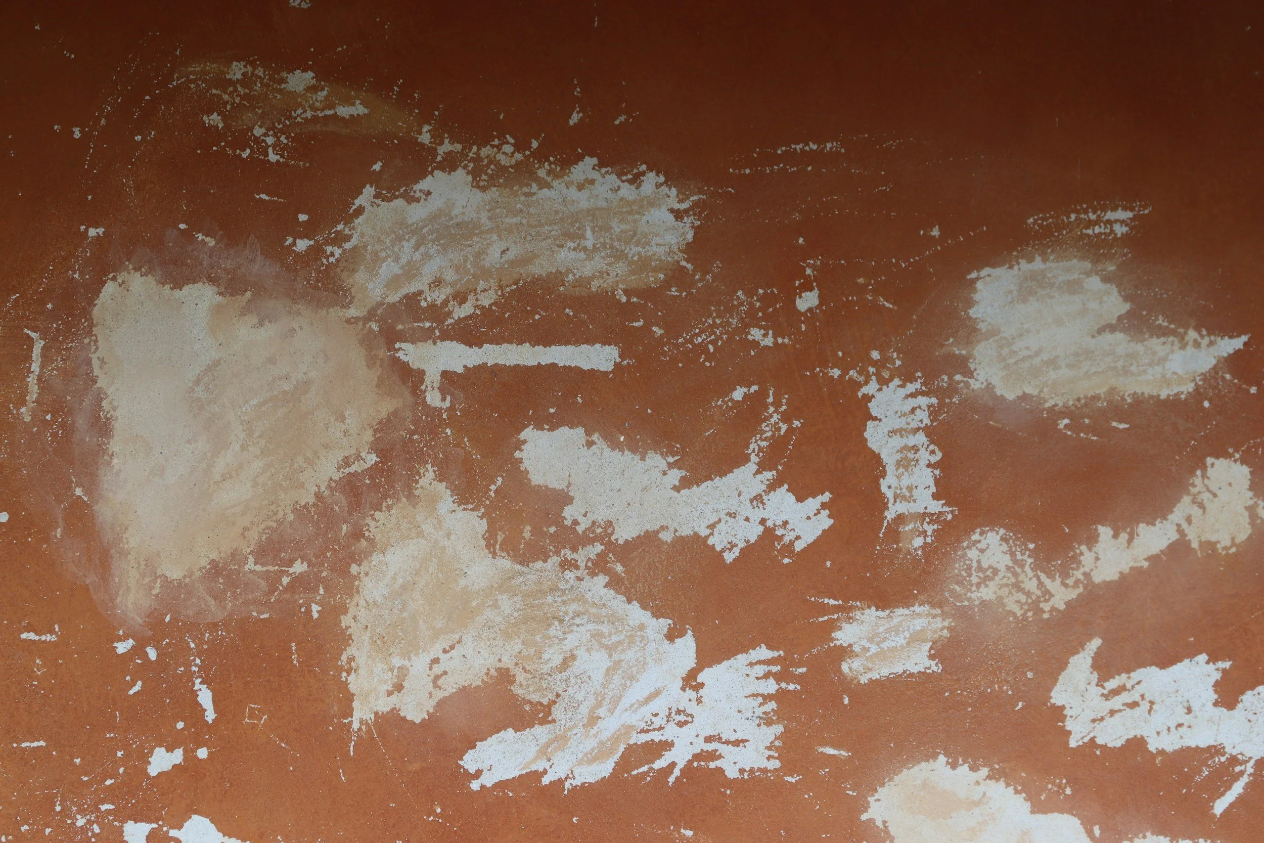 Close-up of a brown surface with patches of white powder scattered unevenly.