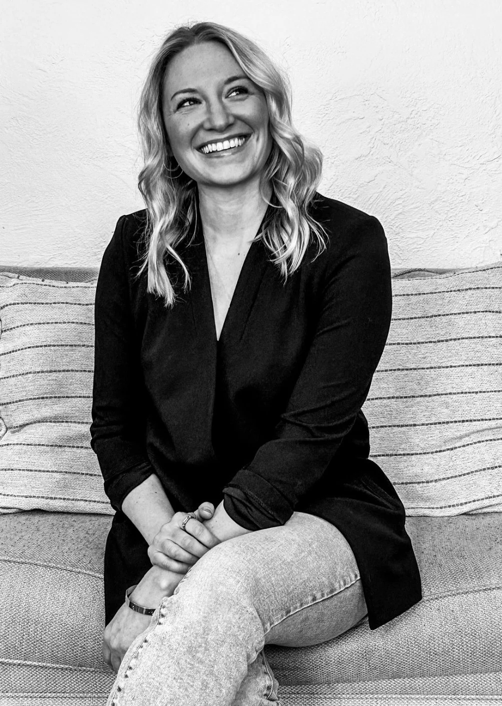 A woman smiling on a couch with striped cushions in black and white