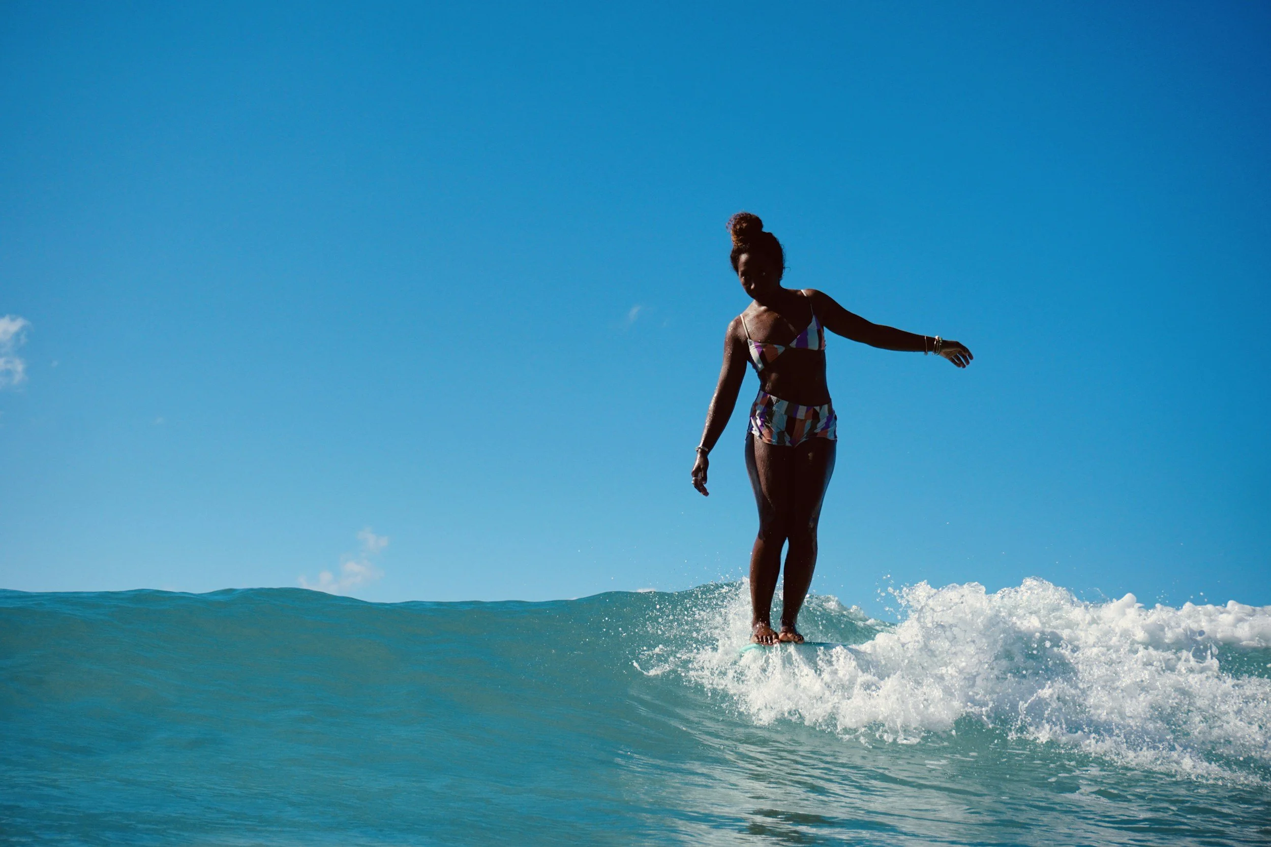 African American women surfing a longboard with toes on the nose jacksonville beach florida