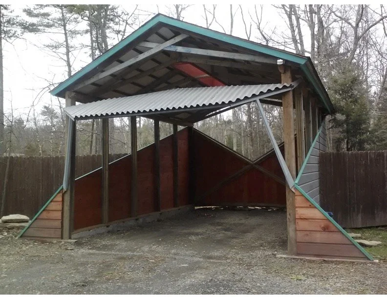 Sculptural wooden carport by Bill Hochhausen with angular red siding and exposed timber framing.jpg