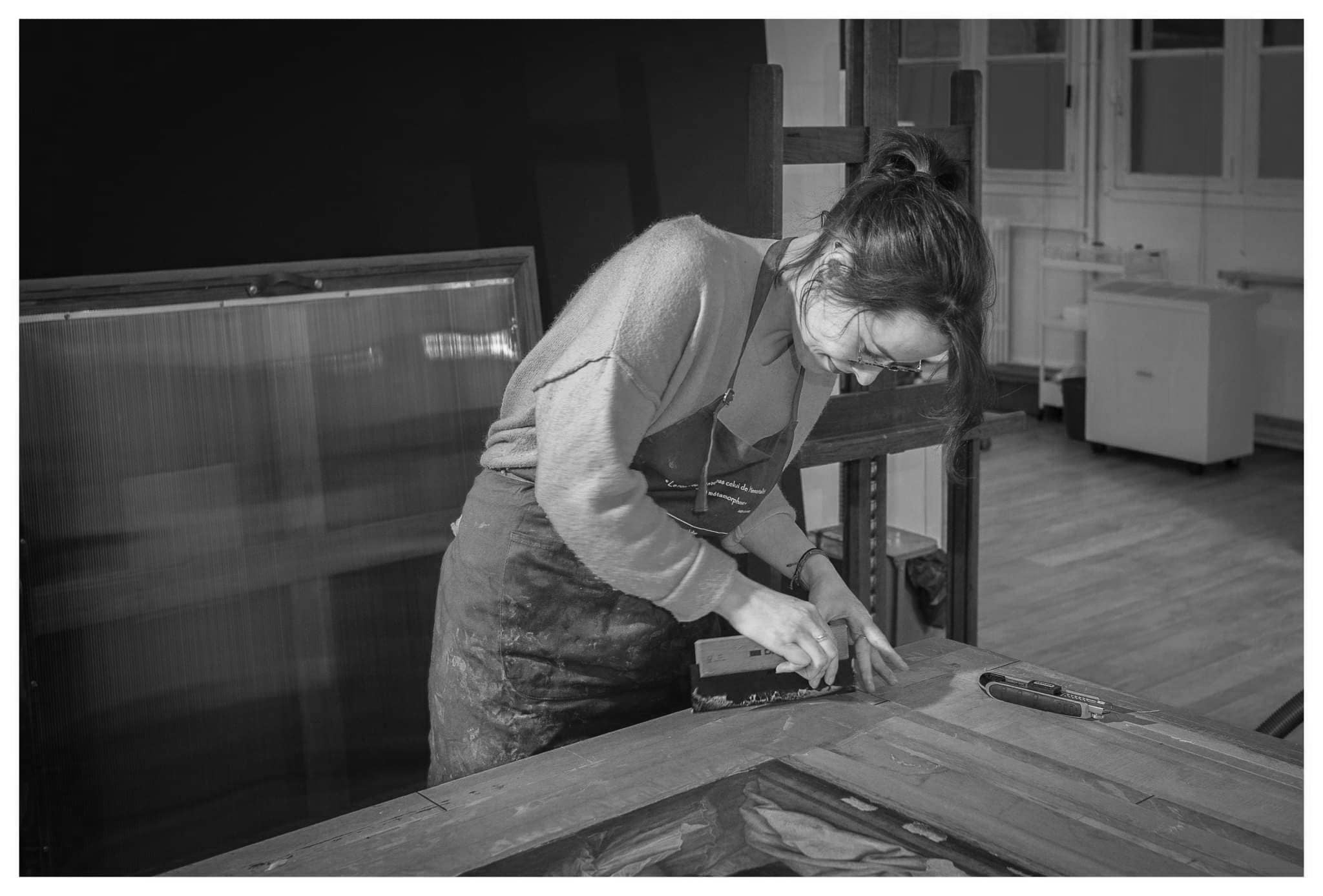 Une femme utilisant une règle de menuisier pour travailler du bois dans un atelier.
