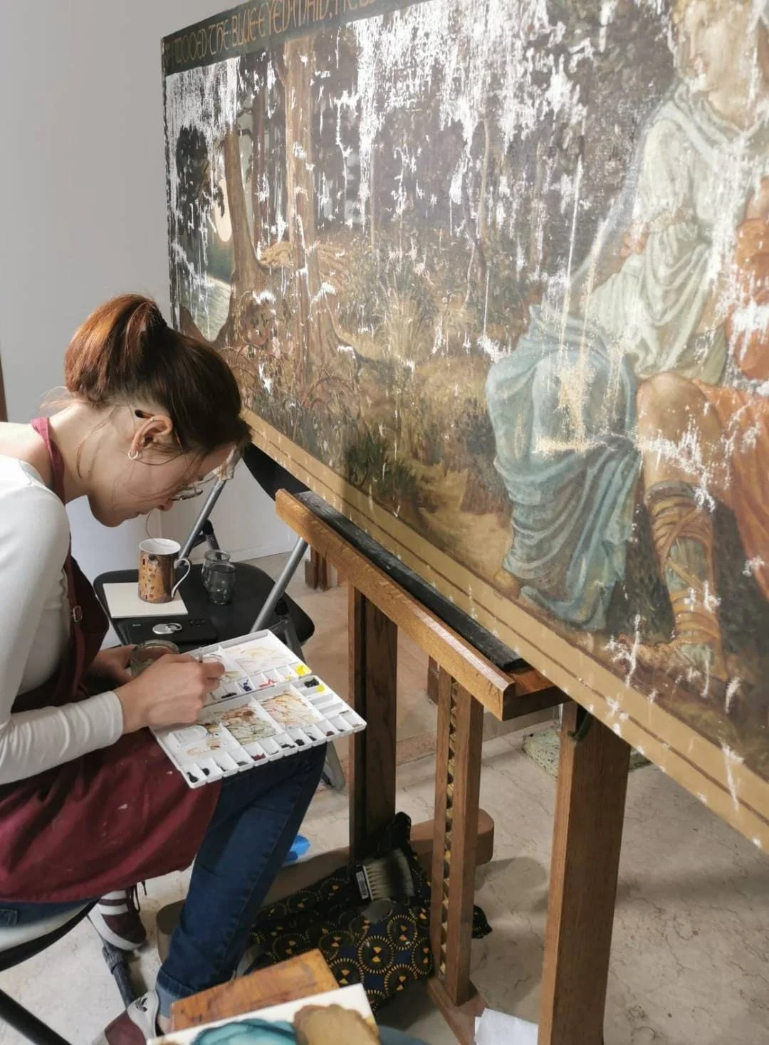 Une femme se peignant une toile ancienne dans un atelier d'art, utilisant une palette de peinture.