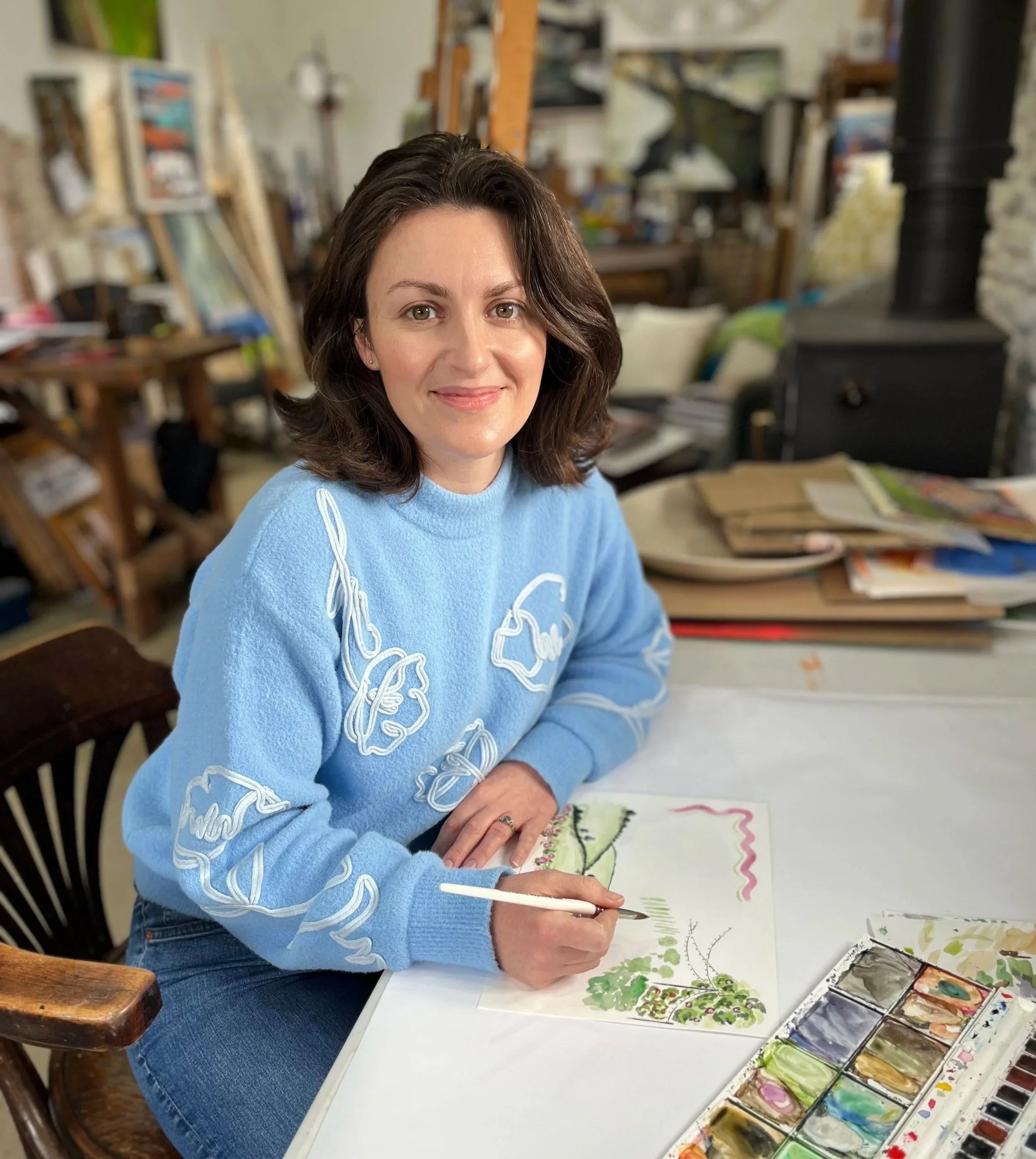 Nic Squires sat at a desk painting a wedding invitation