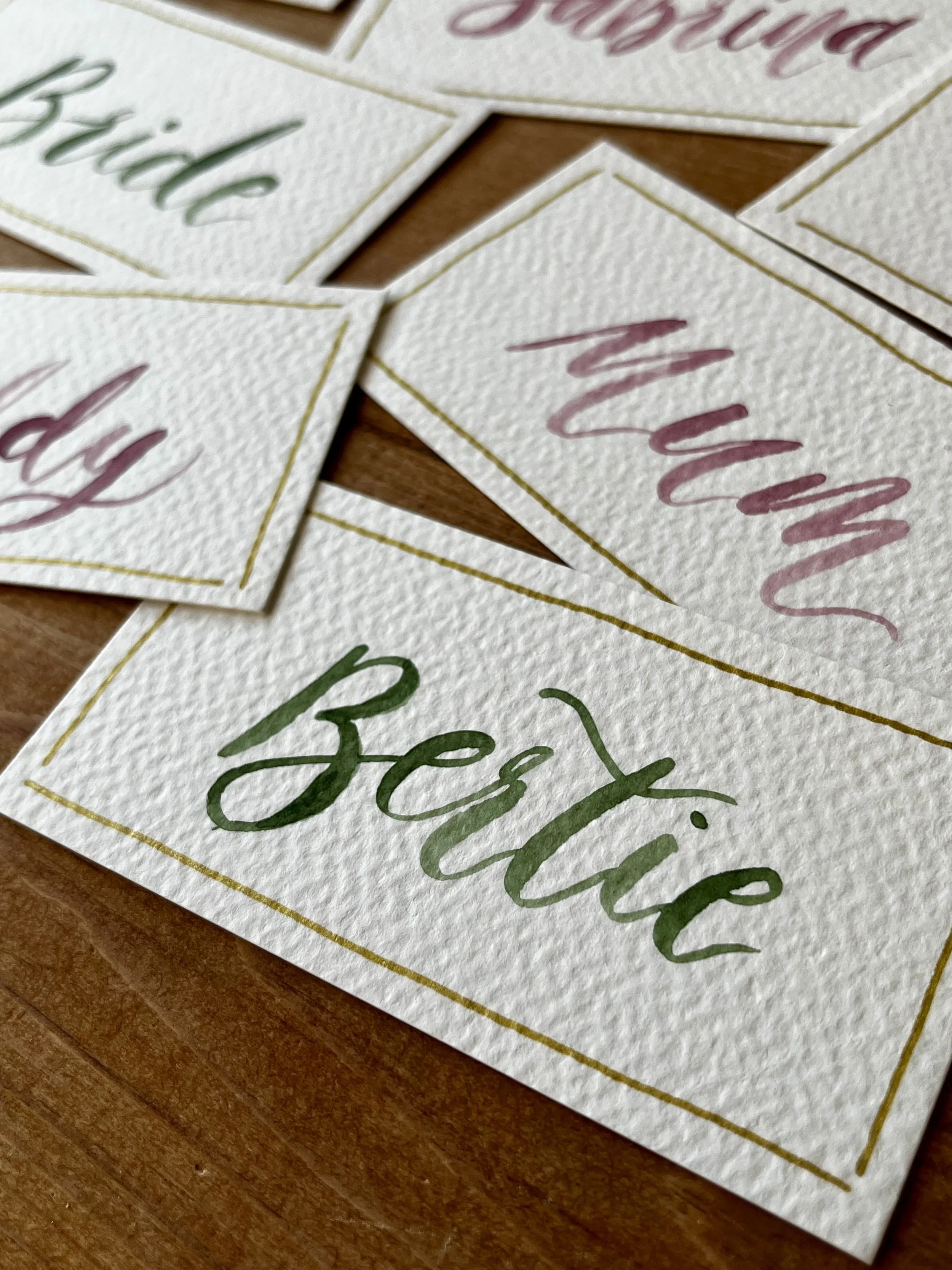 Cards with watercolor calligraphy reading 'Baby', 'Mummy', and 'Big' on textured paper.