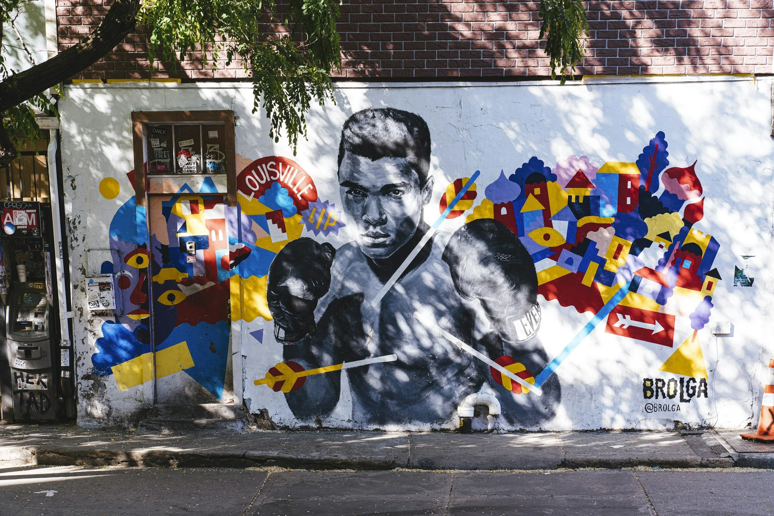 Street art mural of a boxer in black and white on a city wall with colorful geometric shapes and cityscape background.