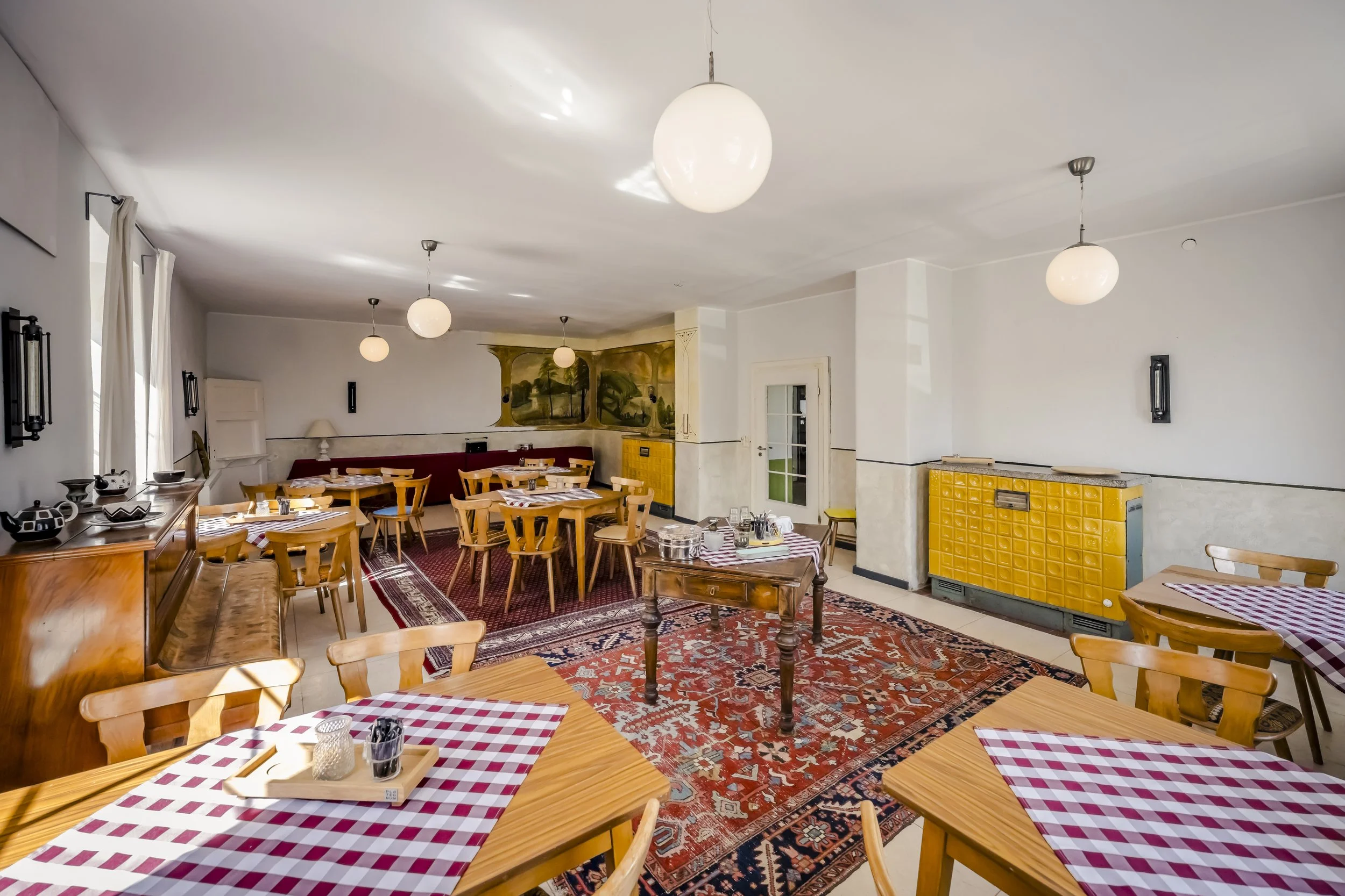 Gemütliches Restaurant mit Holztischen, Stühlen im schwedischen Design, rot-weiß karierten Tischdecken, Teppichboden und moderner Beleuchtung.