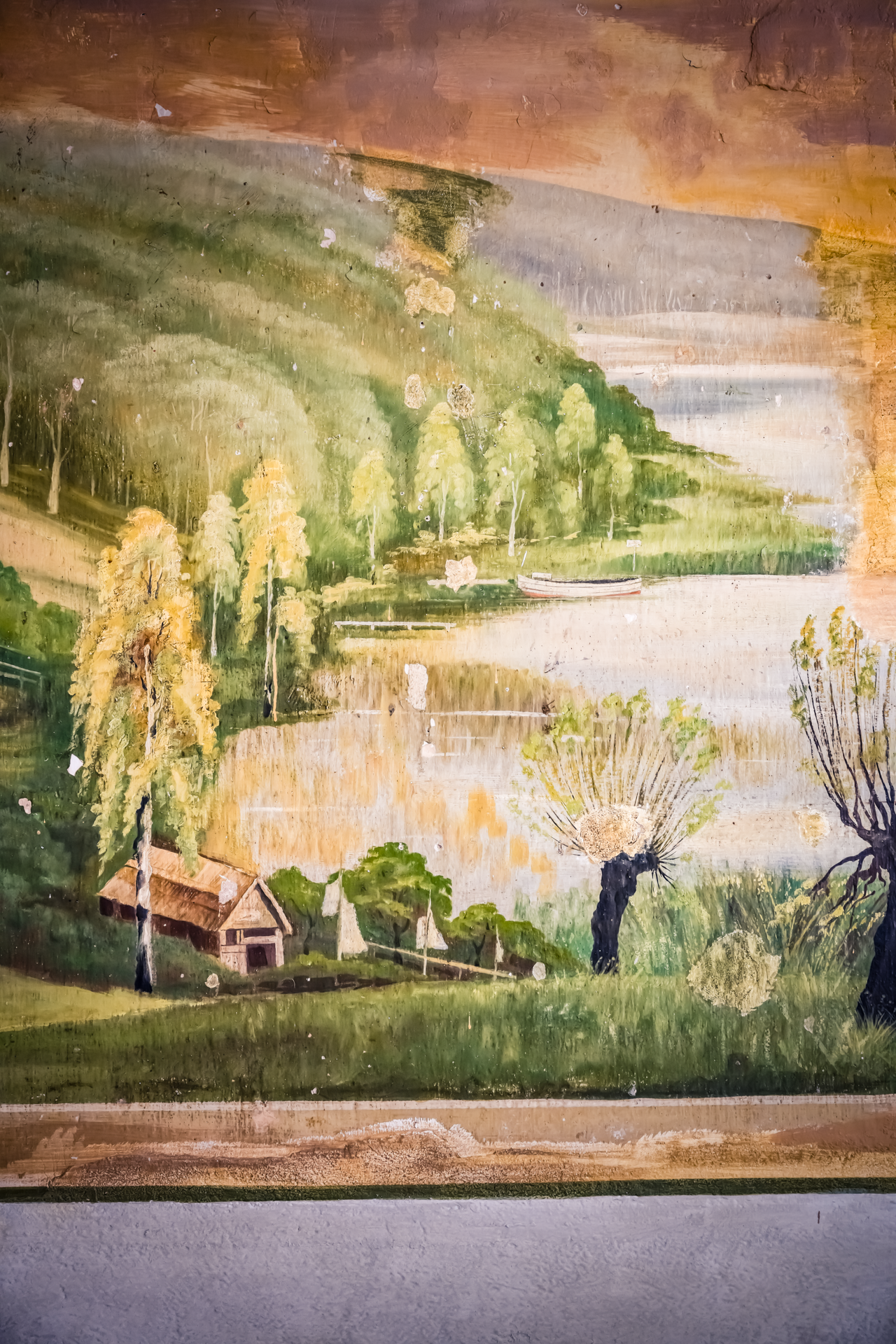 Alte Wandmalerei mit einer Landschaft, Wasser, Bäume, Haus und Berge im Hintergrund.