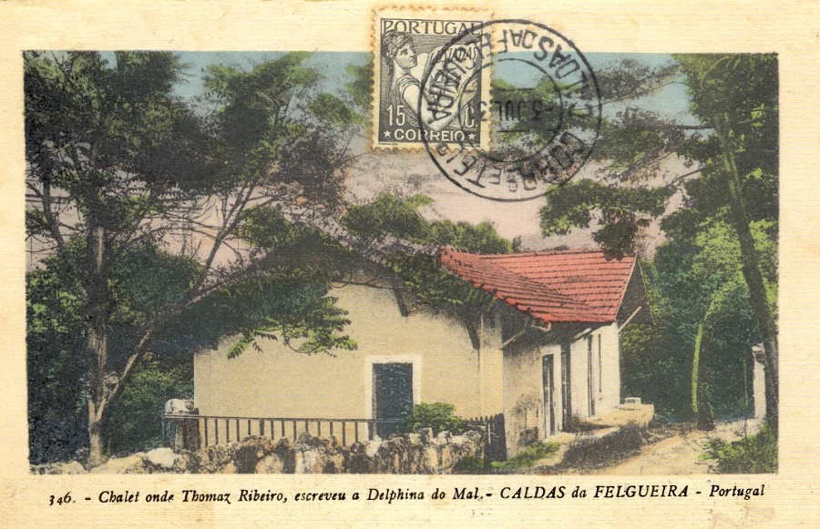 Cena de uma casa tradicional em Portugal rodeada por árvores, com telhado de telhas vermelhas. Há um selo postal e uma marca de carimbo no canto superior direito, indicando que é uma carta enviada do Brasil para Portugal.