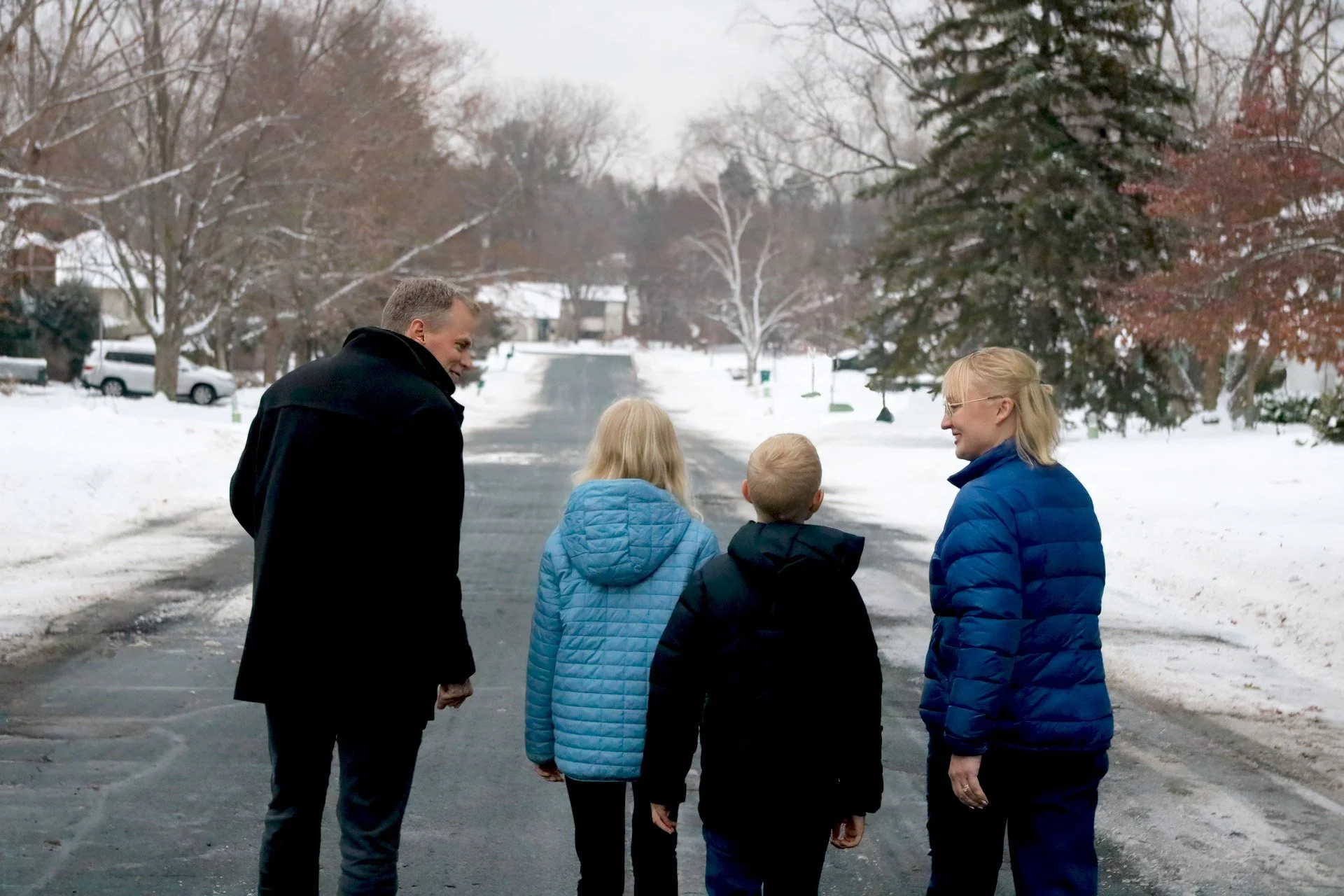 Candidate Aisha Elmquist walking down the street with her family in the snow.