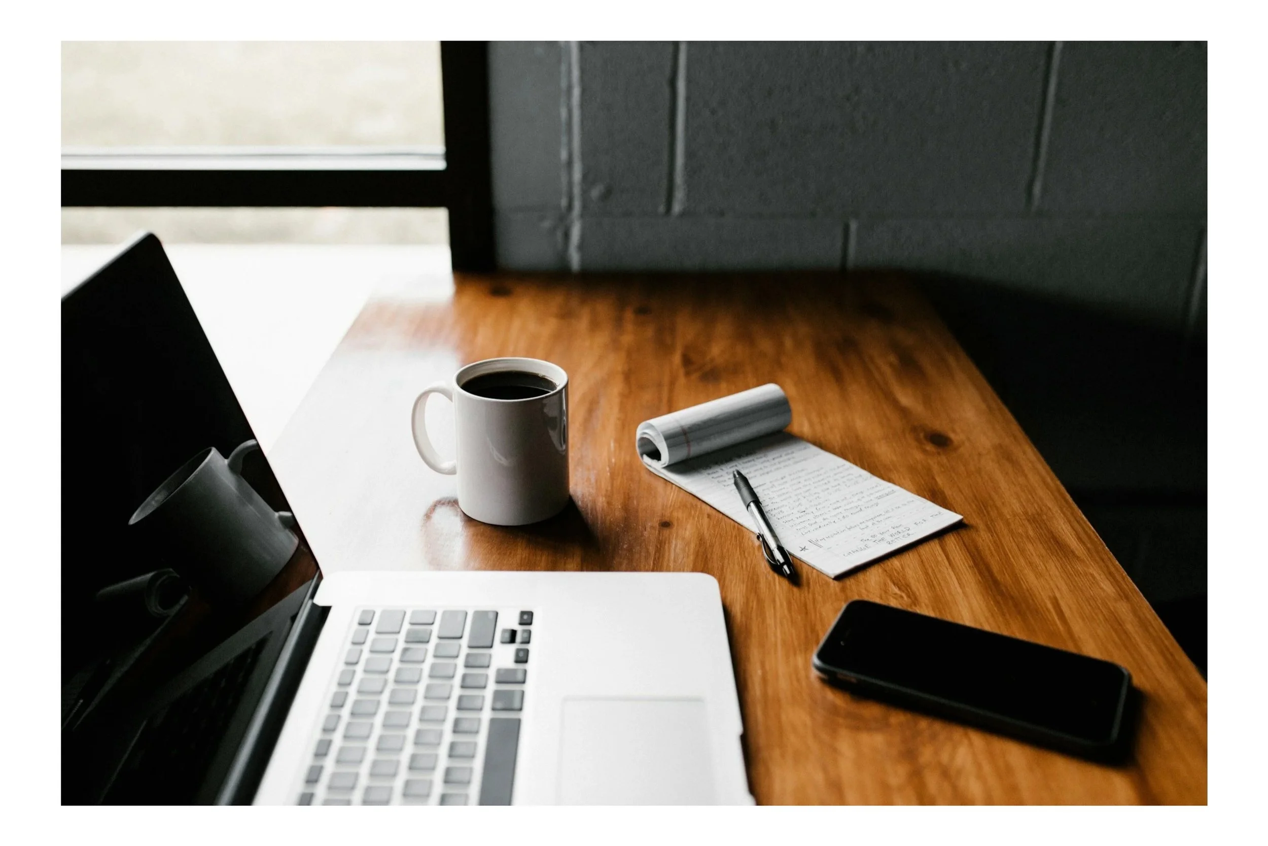 Modern house on a green hillside with snow-capped mountains in the background under cloudy sky.