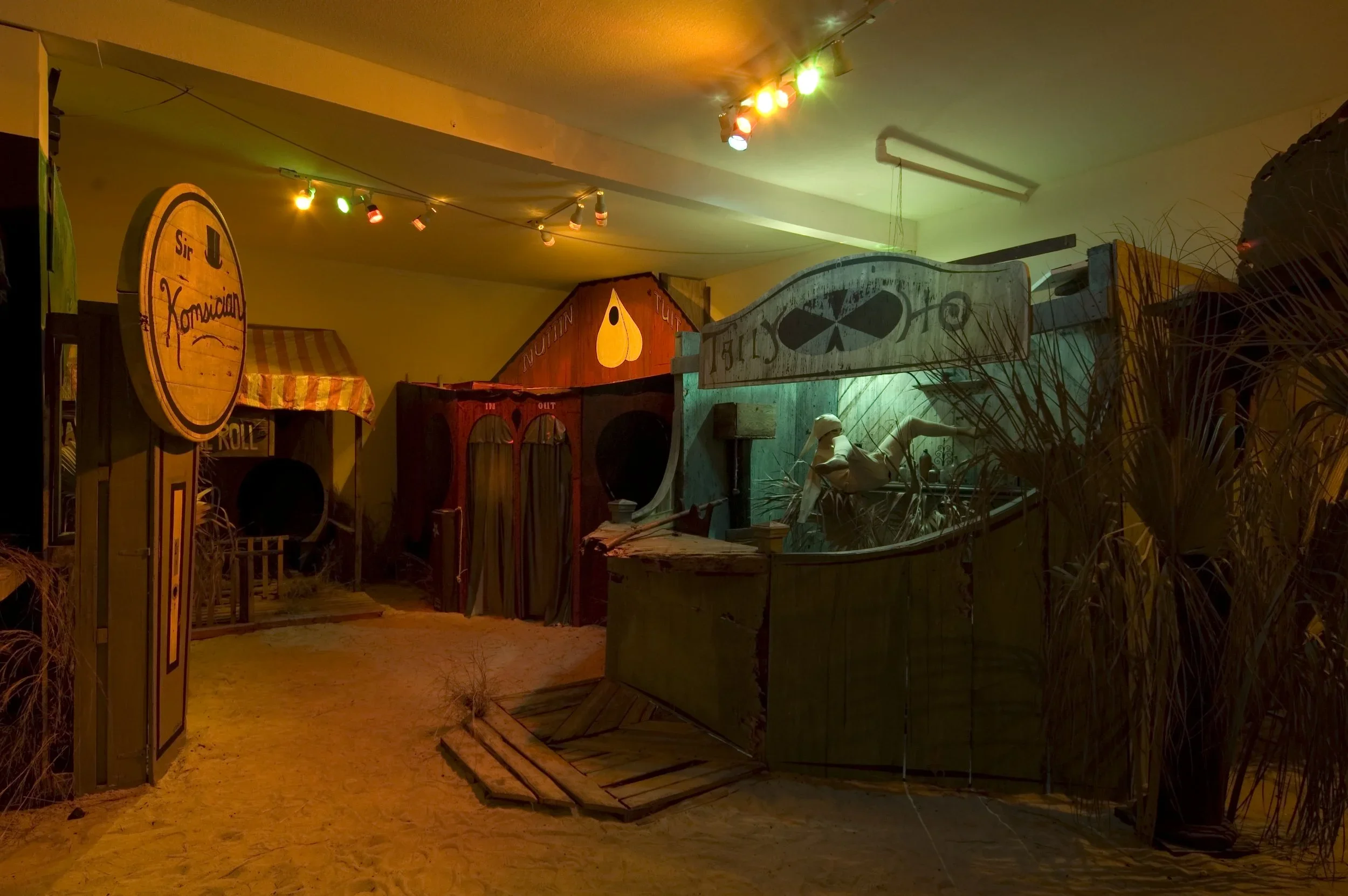 Indoor display with seashell and pirate-themed decorations, including a wooden sign, sand floor, and pirate props.