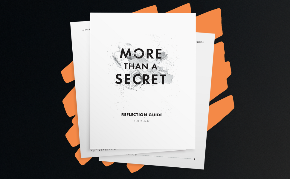 A reflection guidebook titled 'More Than a Secret' by Alicia Barr is displayed on top of other papers with orange paper clips on a black background.