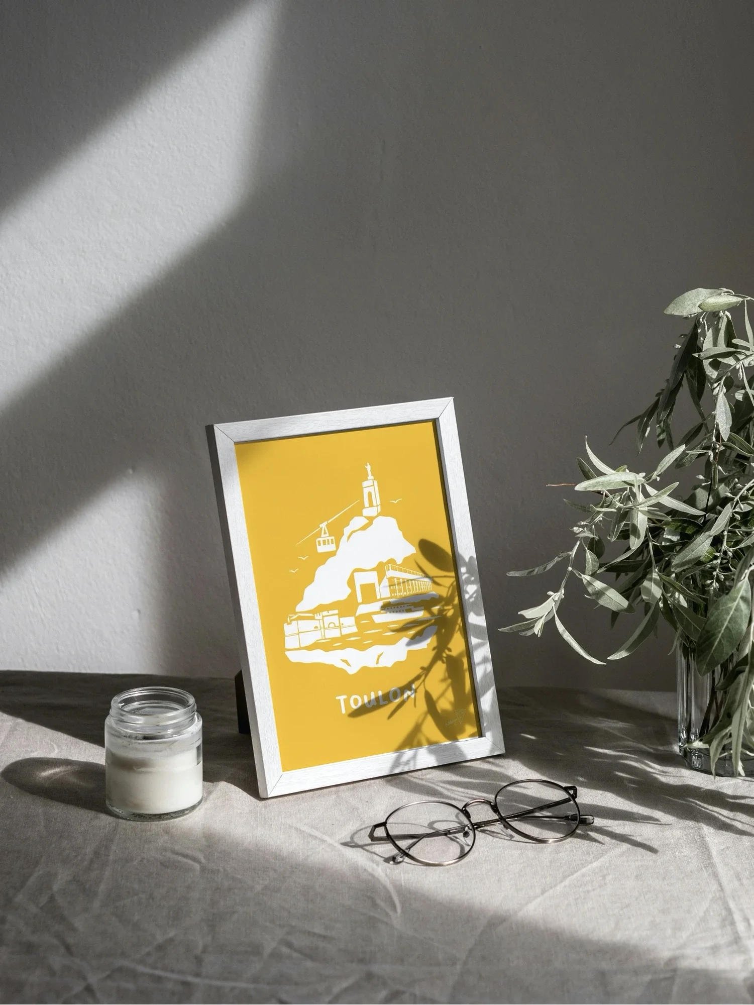 Affiche Toulon encadrée dans un intérieur lumineux, illustration jaune et blanche de la région