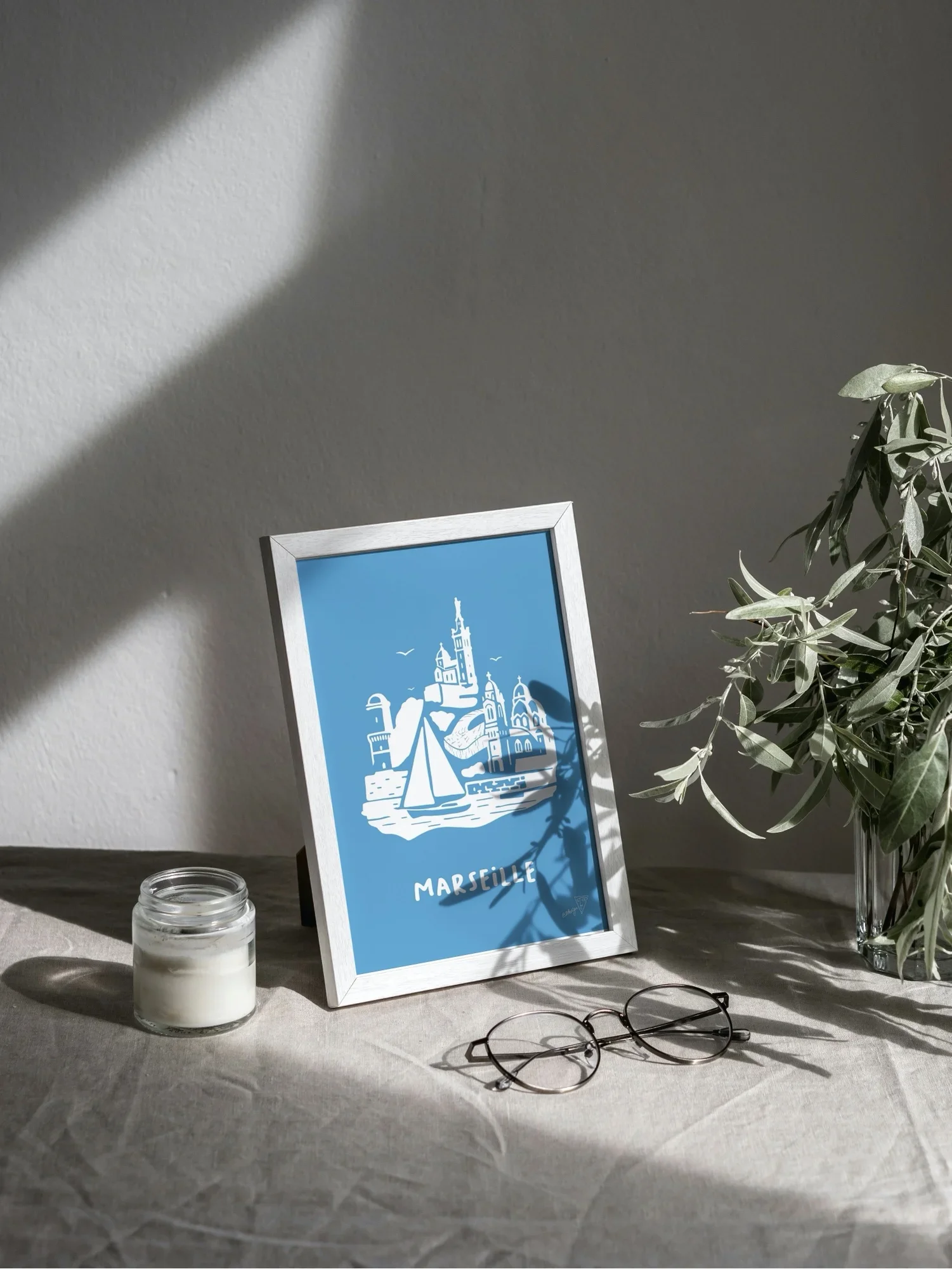 Affiche Marseille encadrée dans un intérieur lumineux, illustration bleu et blanche de l'Olympique de Marseille
