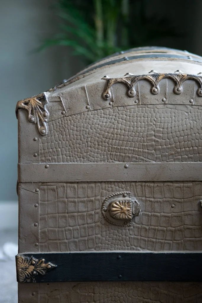 Close-up of a vintage, first-class style travel trunk with decorative metal accents and textured patterns.