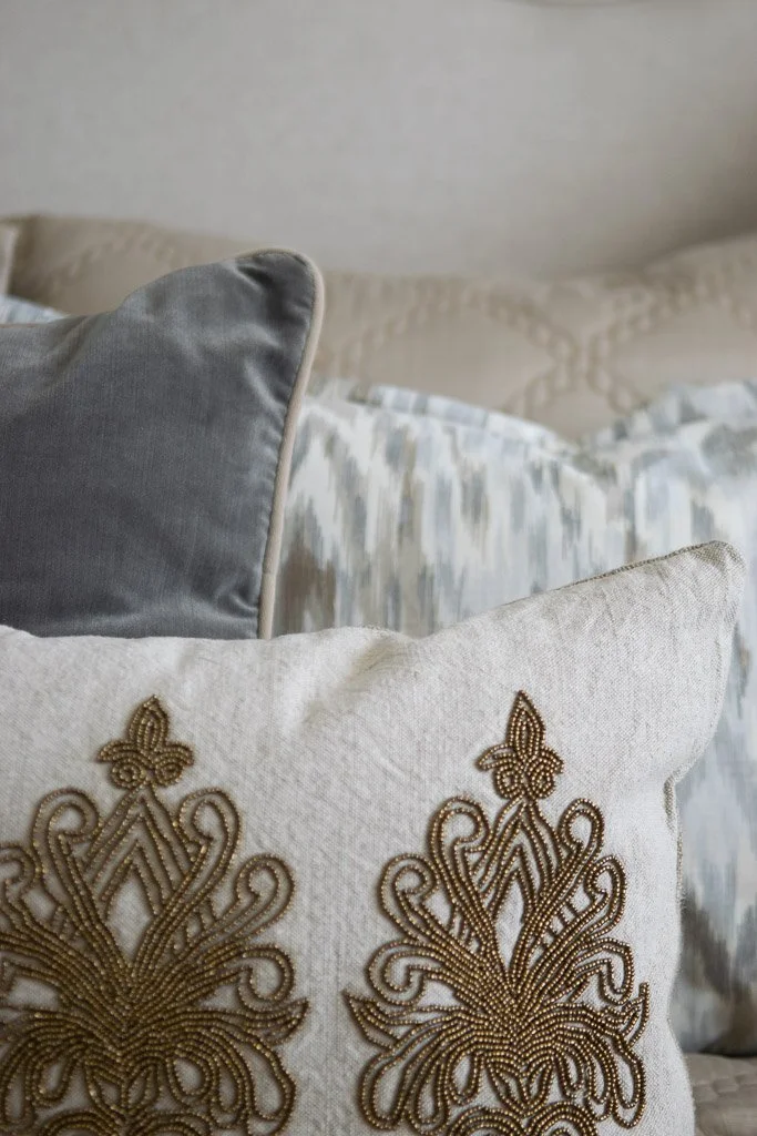 Decorative pillows on a bed, featuring ornate embroidery and different fabric textures.