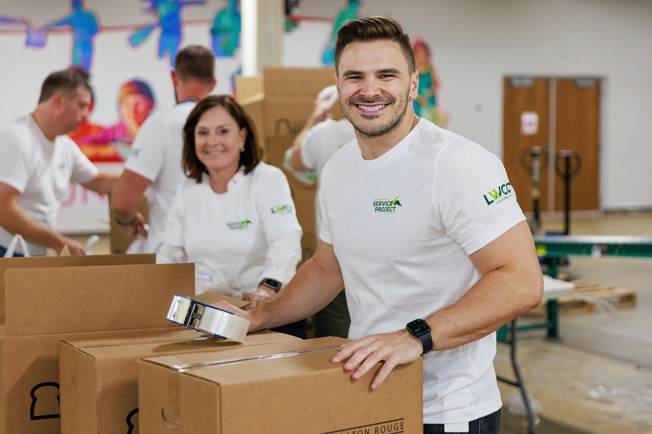People packing boxes for a service project at an indoor community space.