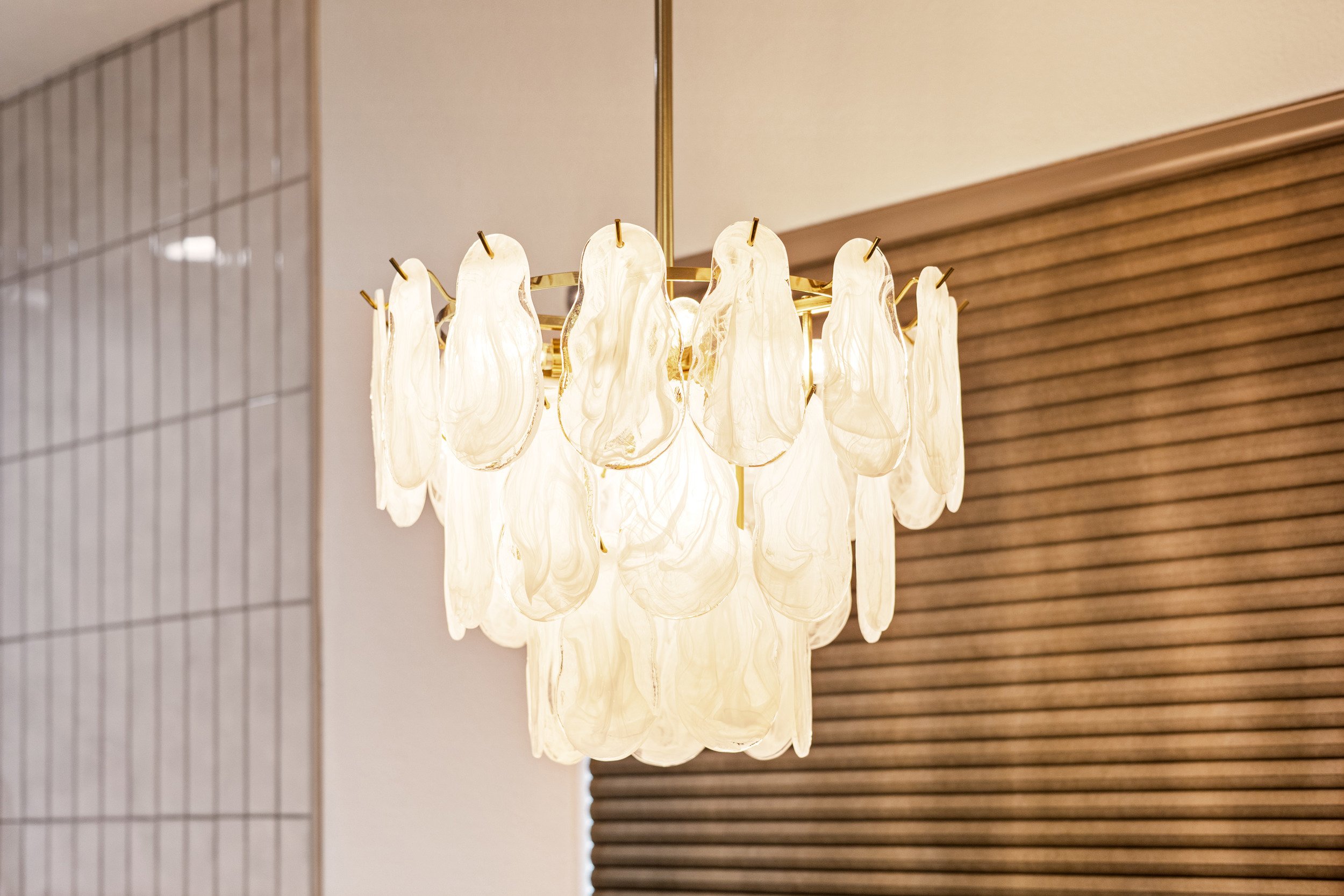 A chandelier with multiple cream-colored, shell-like panels hanging from a brass frame.
