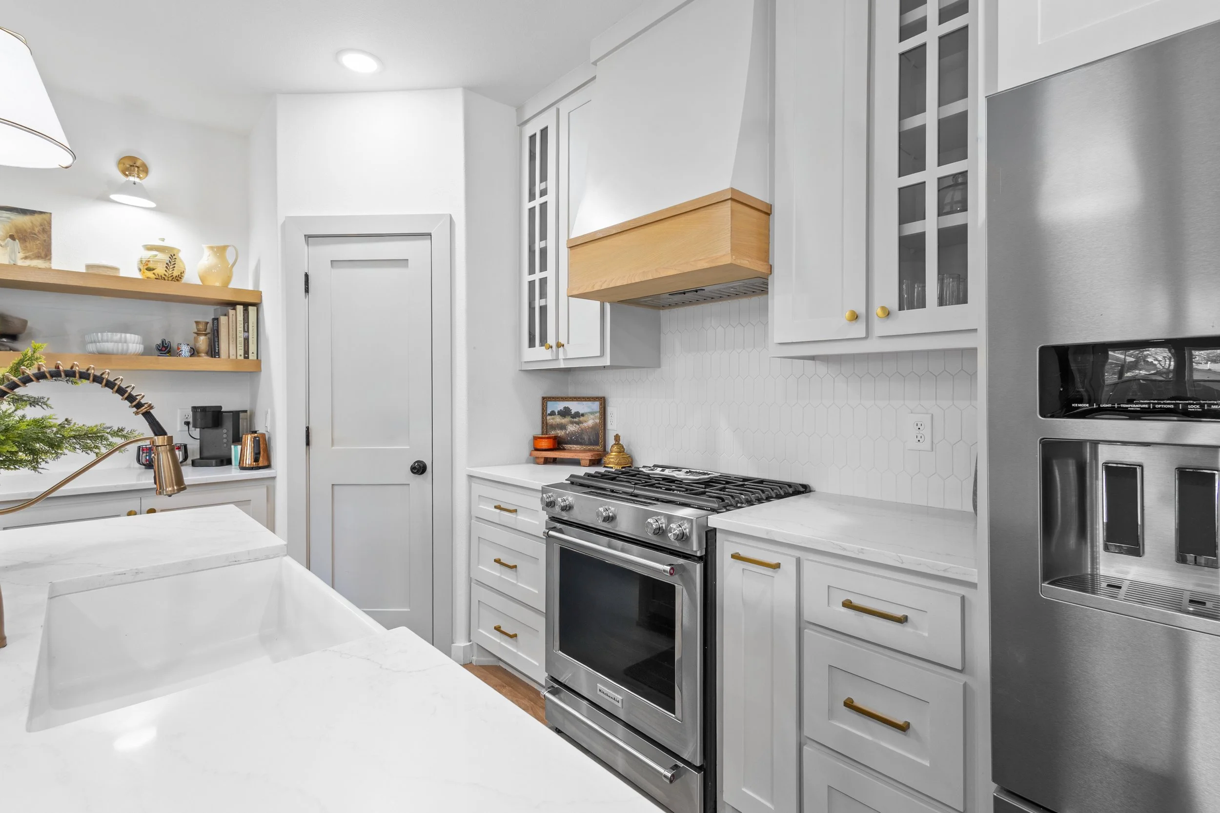 White kitchen with stainless steel oven, glass-front cabinets, and wooden accents.