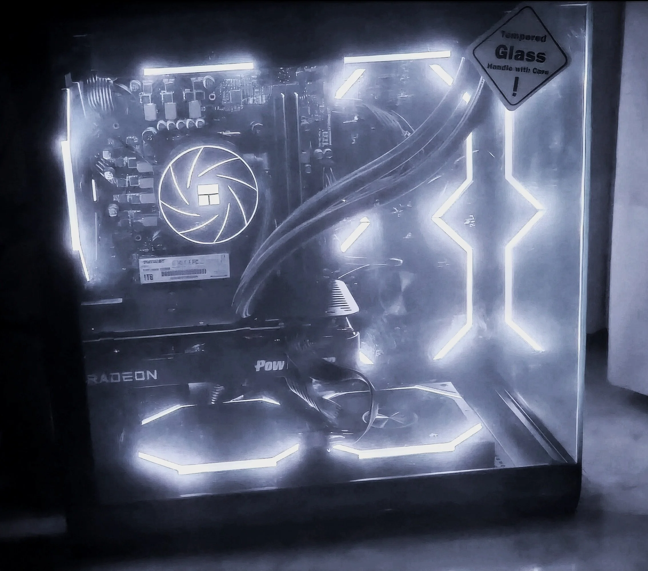 Computer inside a glass case with LED lighting, showing a graphics card and internal components.