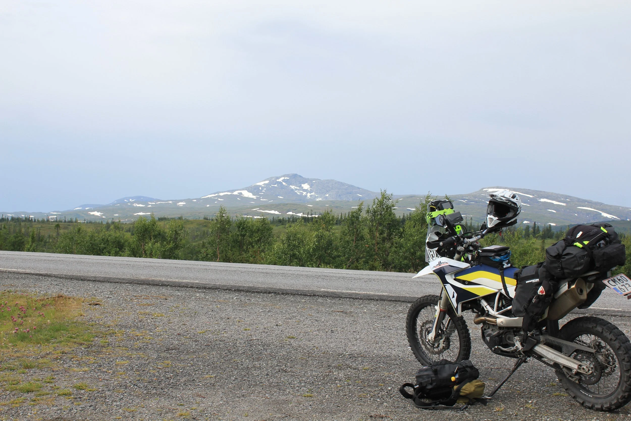 Husqvarna 701 Enduro alongside a road in Sweden. Mountains of Norway in the background.