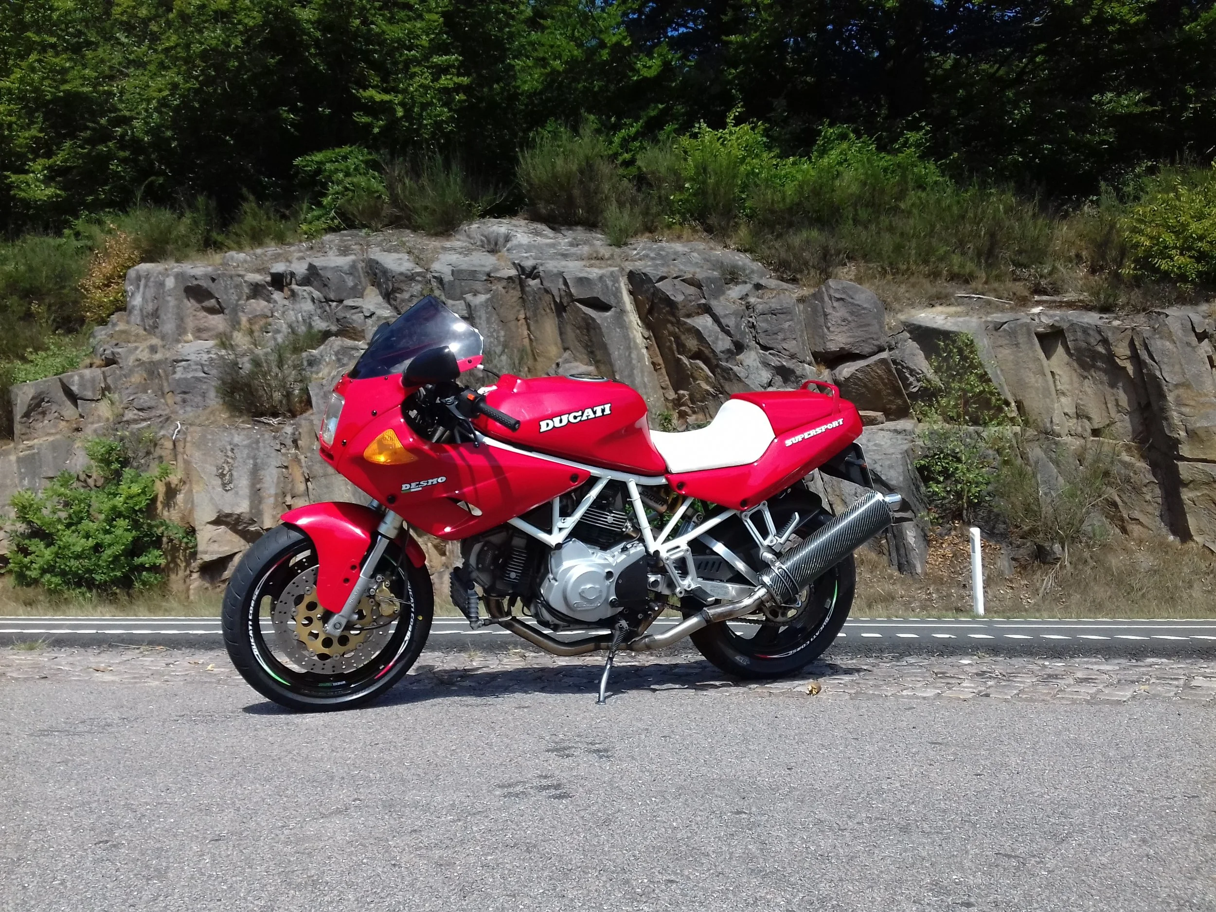 red ducati supersport 750 with a rock face as backdrop 
