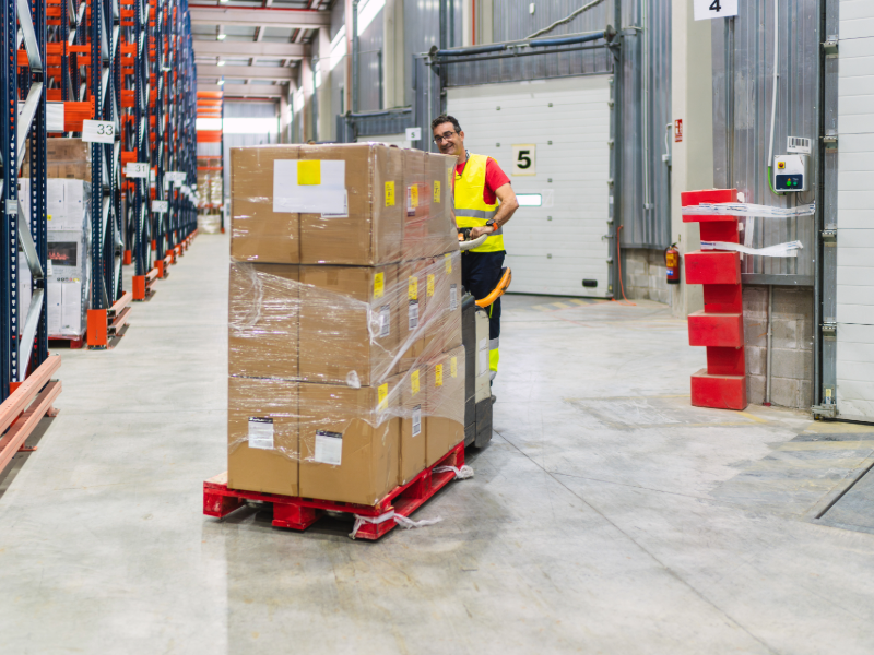 man with pallet of cardboard boxes in warehouse