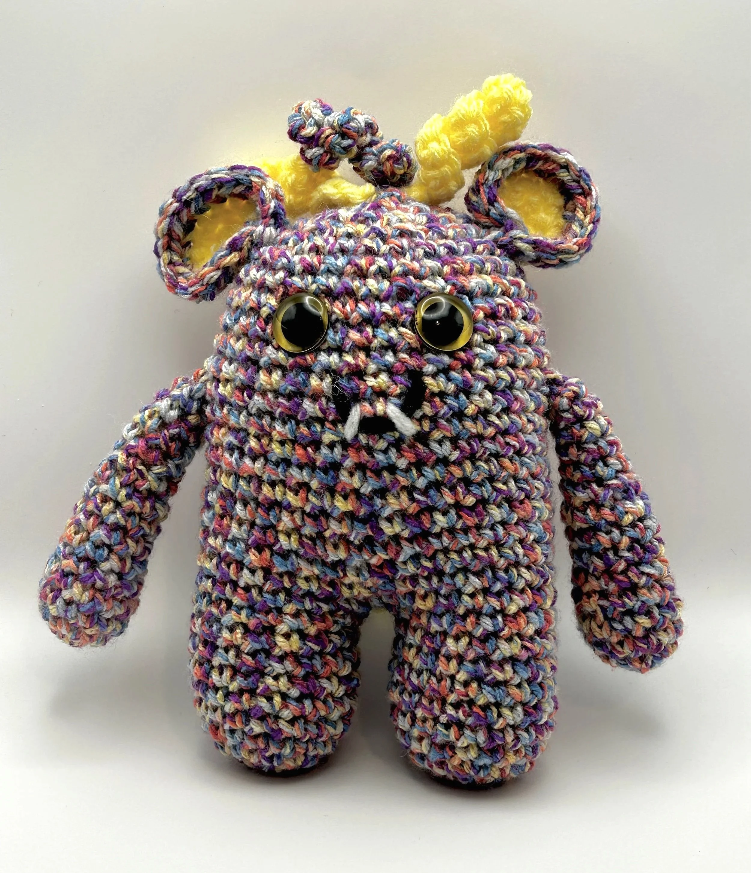 Jimmy blend of purple, orange, and yellow monster with yellow ears, yellow squiggly hair, yellow googly eyes, smiling with 2 teeth