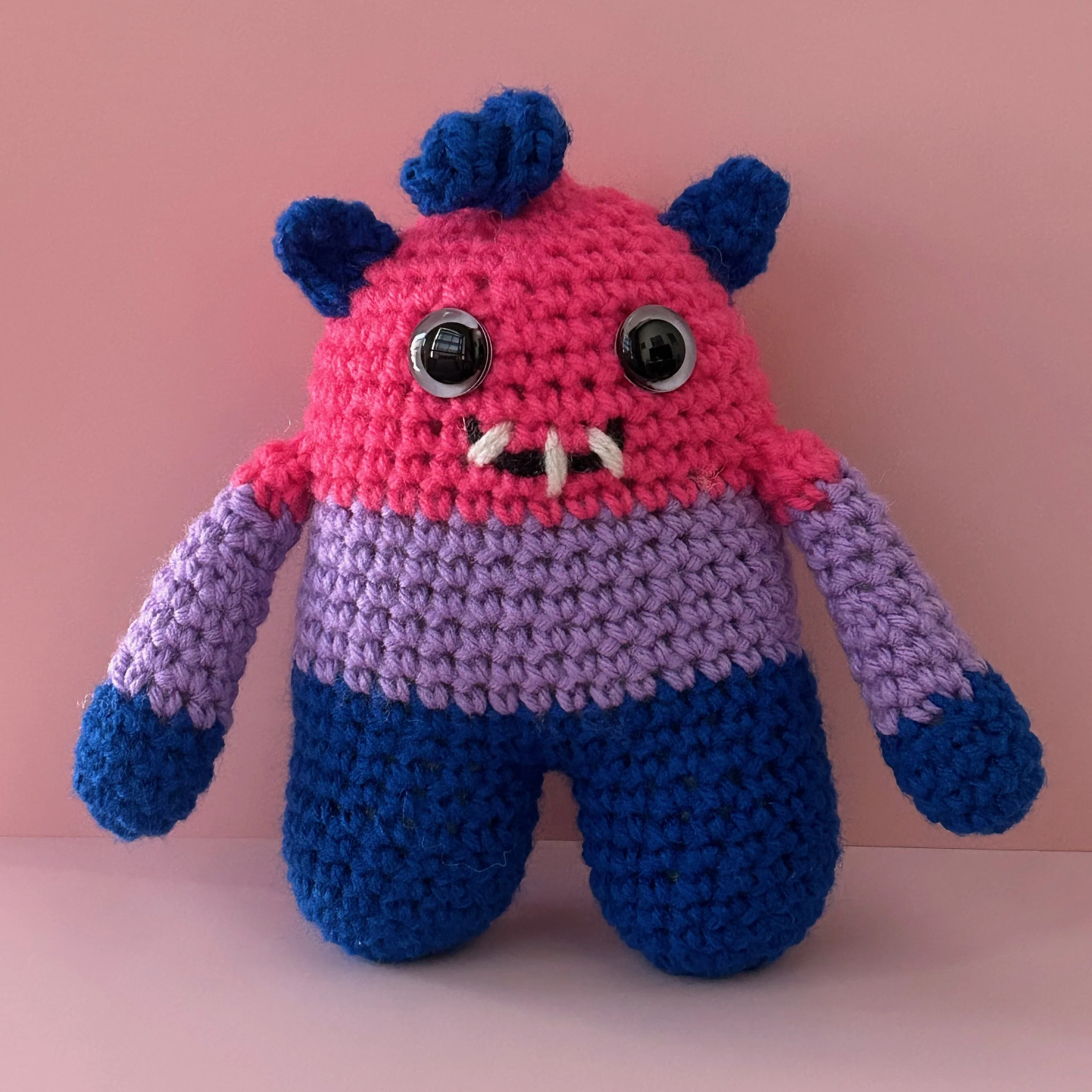 Mica friendly monster plushie bisexual pride flag magenta lavender royal blue stripes googly eyes blue ears blue squiggle hair smiling with 3 teeth