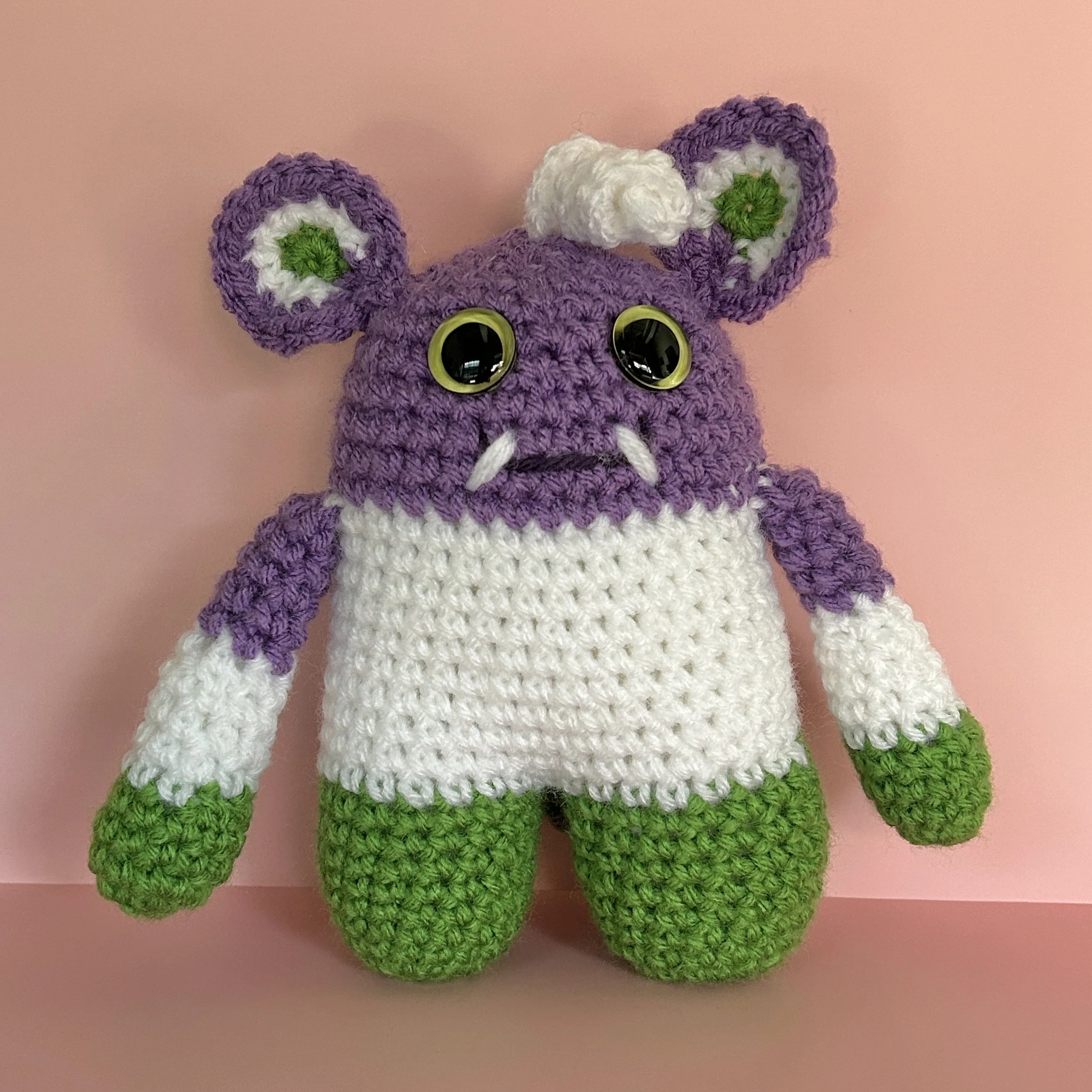 friendly purple white and green striped monster with round ears white squiggle hair light green googly eyes smiling with 2 teeth