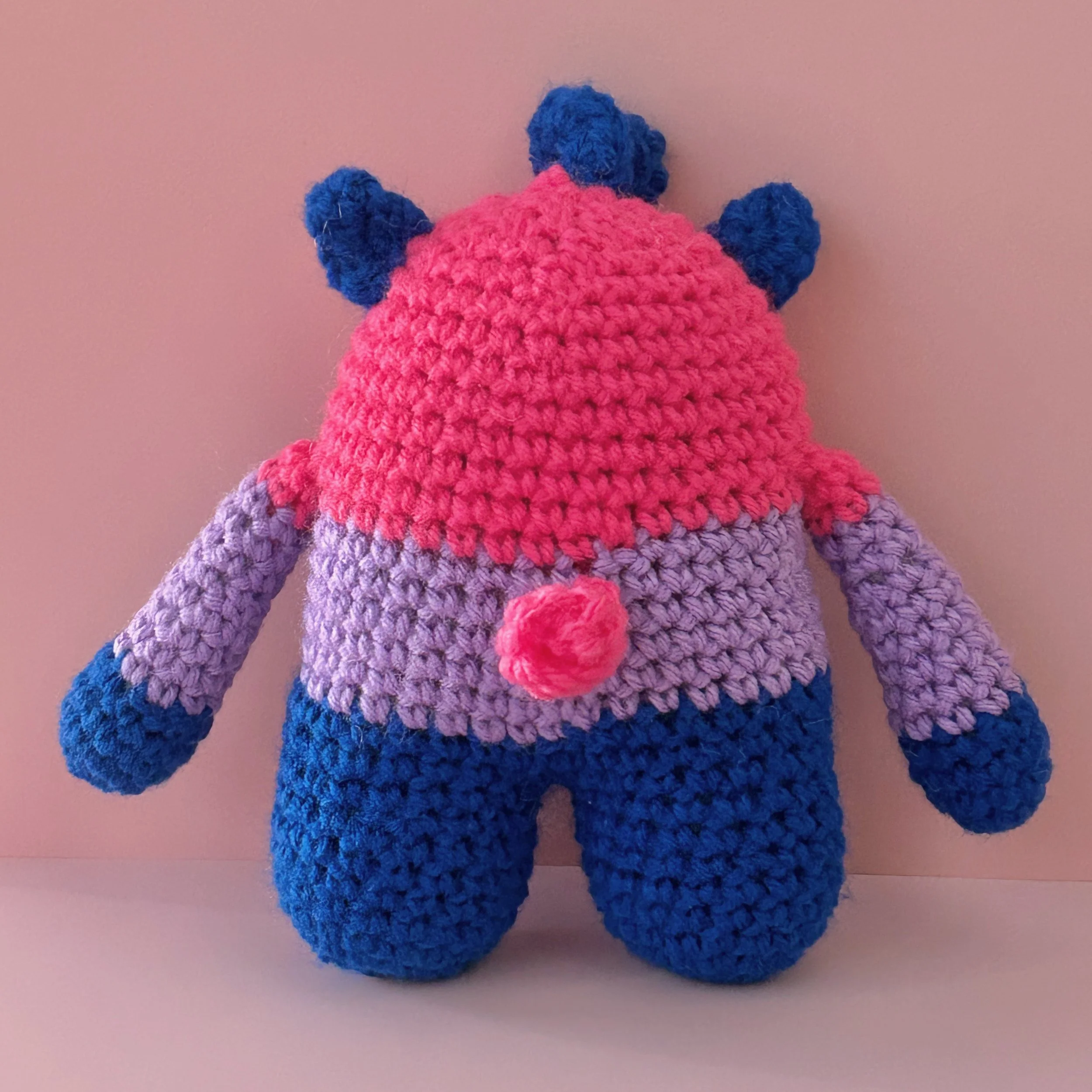 back of monster plushie bisexual pride flag magenta lavender royal blue stripes blue squiggle hair curly pink tail