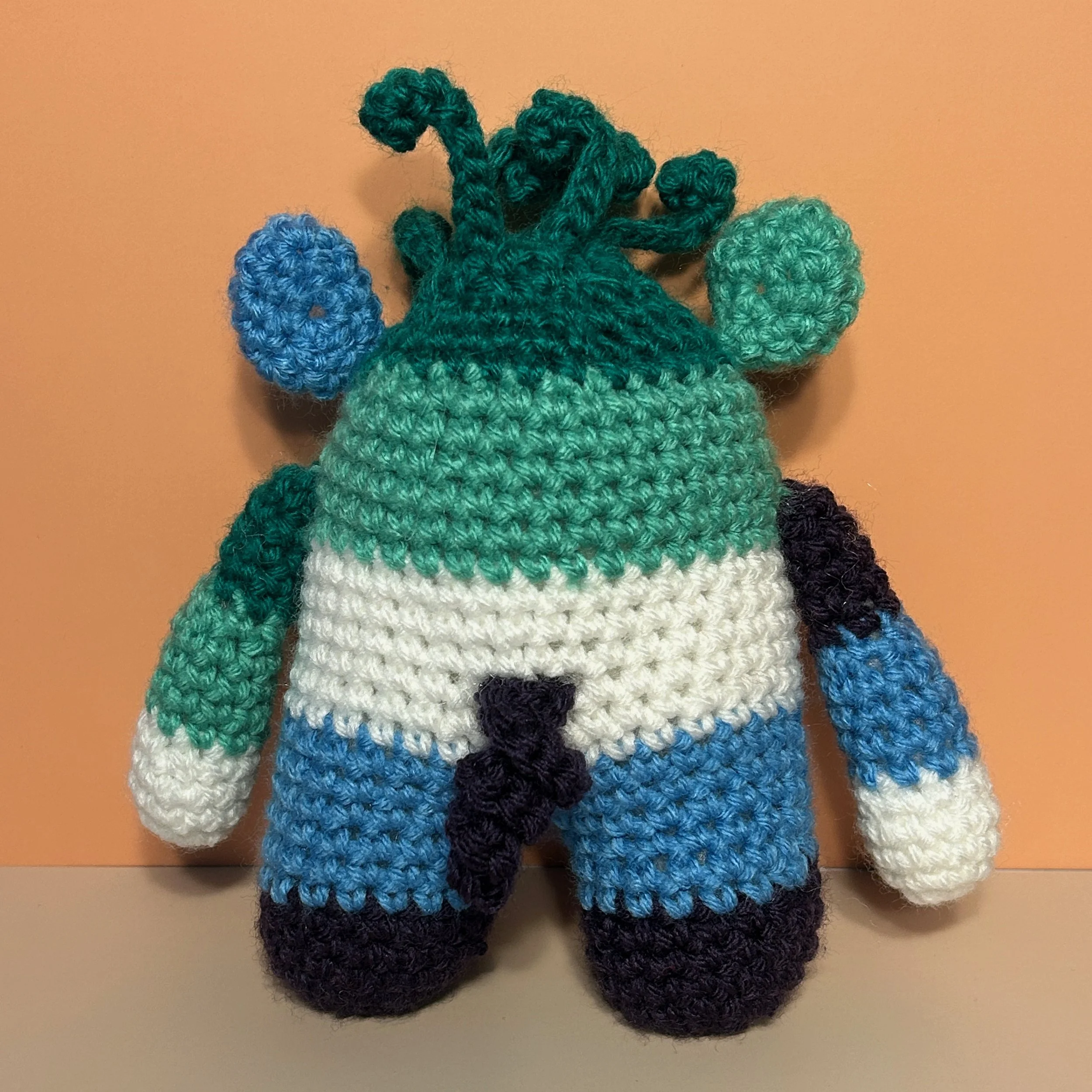 Jack back of green jade white light blue indigo striped monster with medusa-style hair, round ears, and curly indigo tail