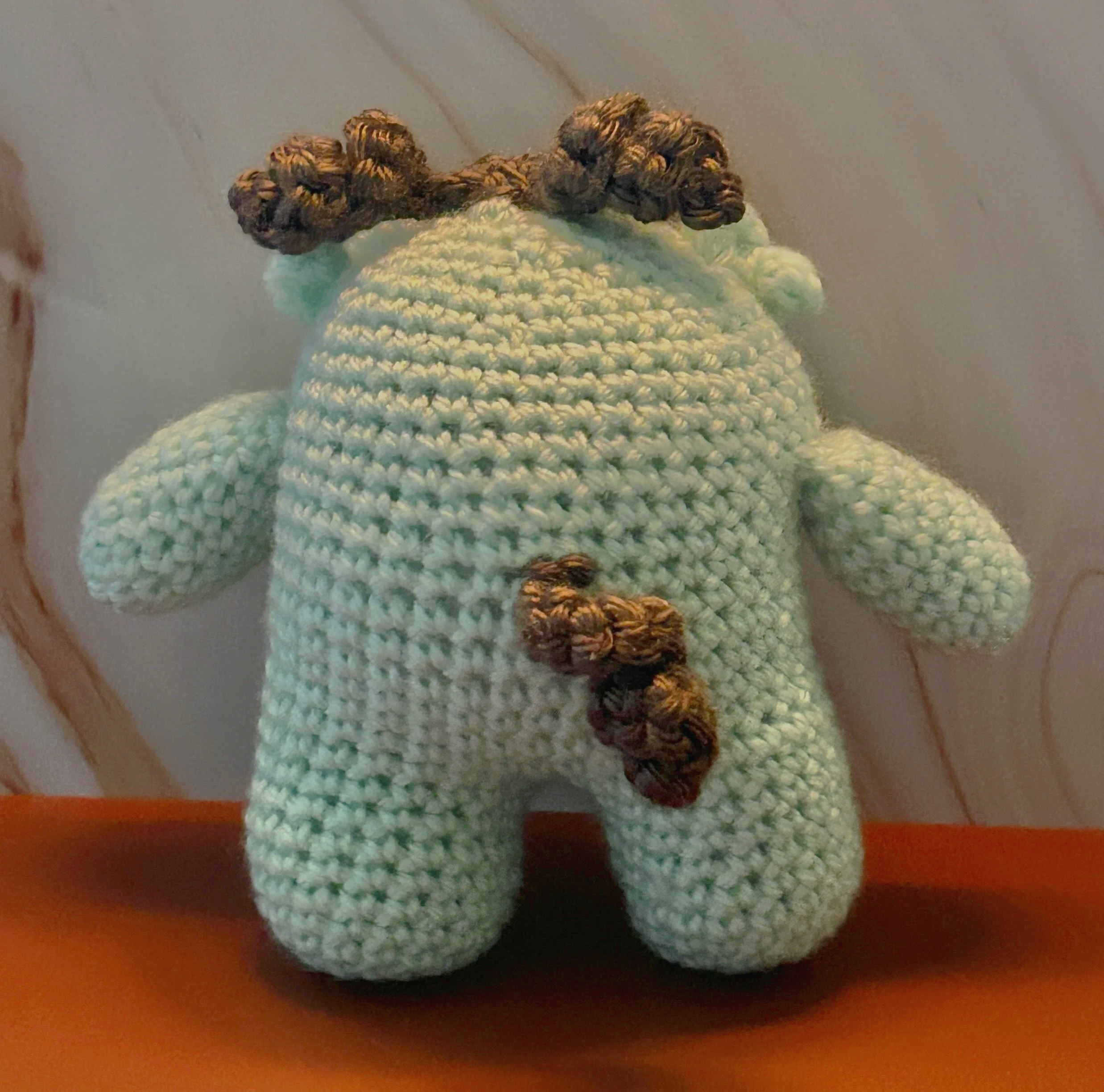 Cocominty back of mint green monster with curly brown tail and hair