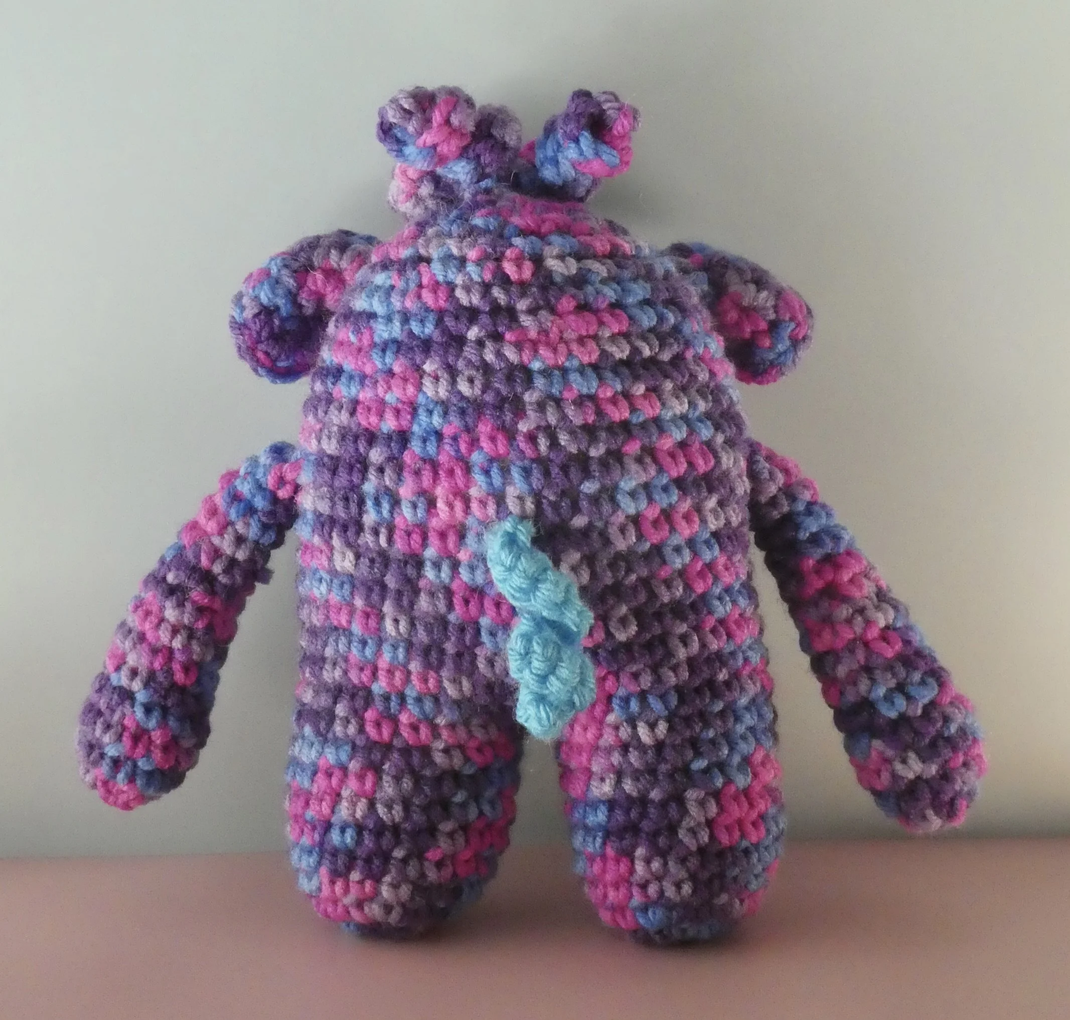 Beryl back of purple and bright pink monster with curly light blue tail