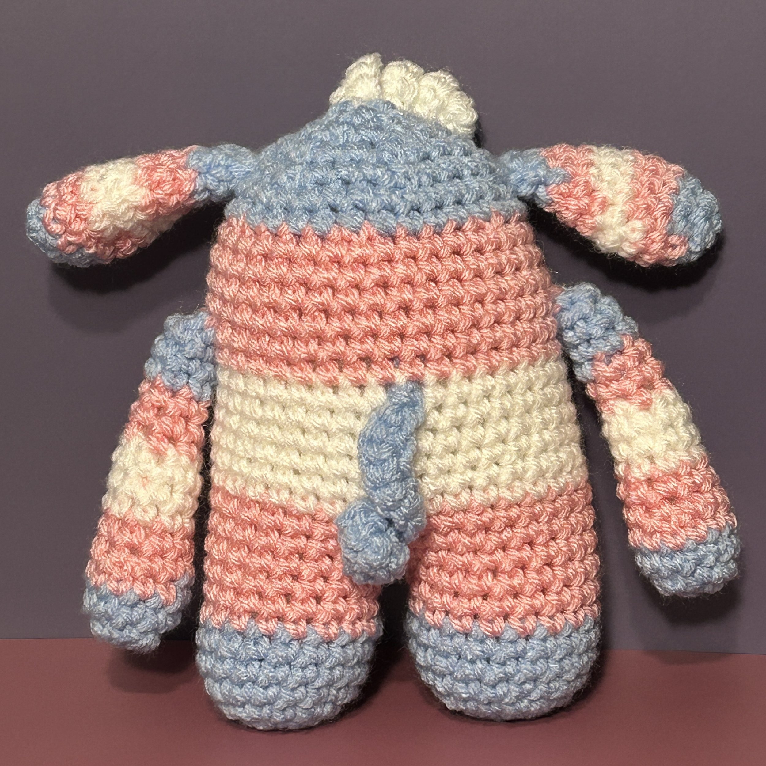 Nicci back of light blue pink and white striped monster and bunny ears and blue curly tail