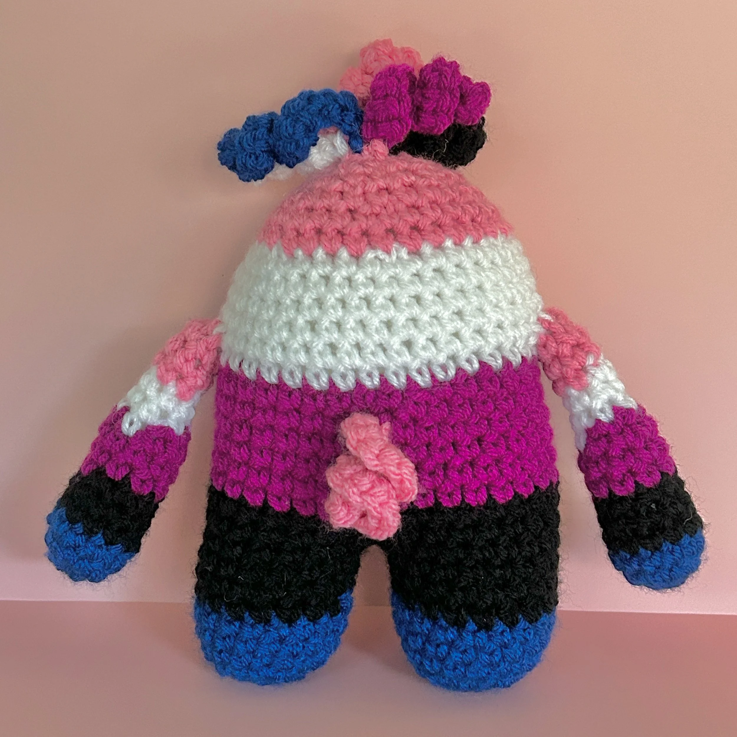 back of pink, white, purple, black, and blue striped monster with squiggly hair and pink squiggly tail