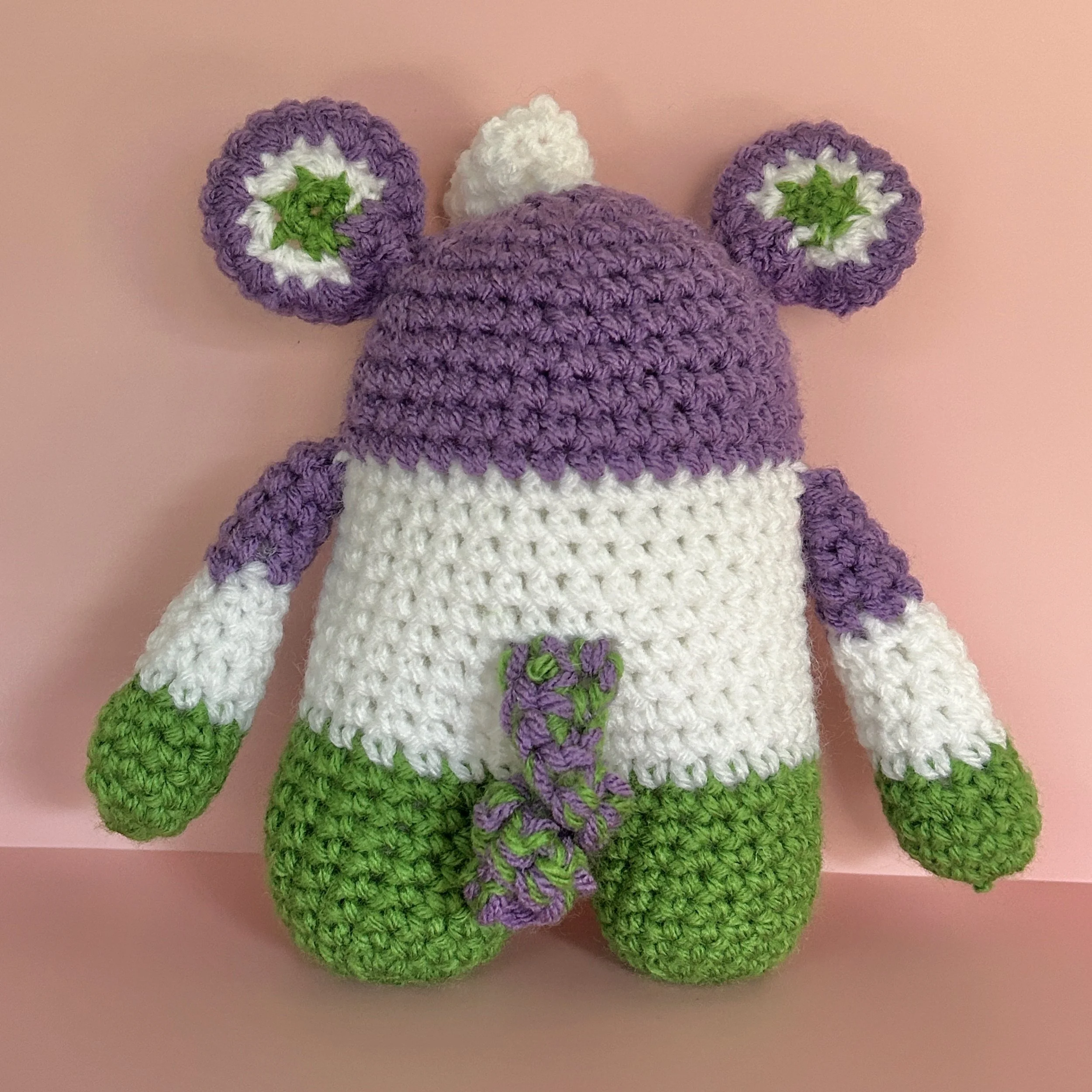 back of purple white and green striped monster with round ears and a green and purple curly tail