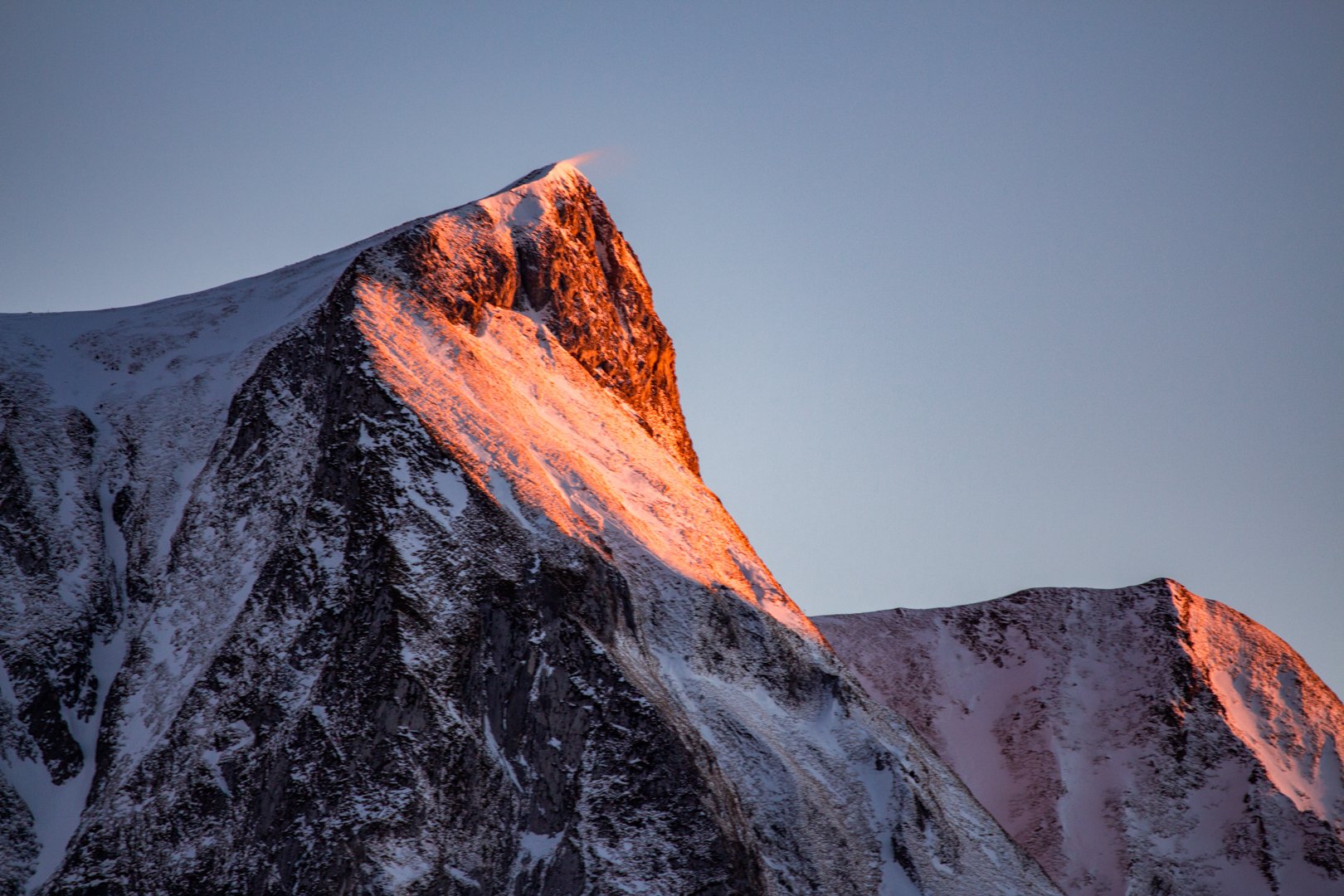 Snow-covered Gantrisch mountain peak illuminated by the orange light of the setting sun.