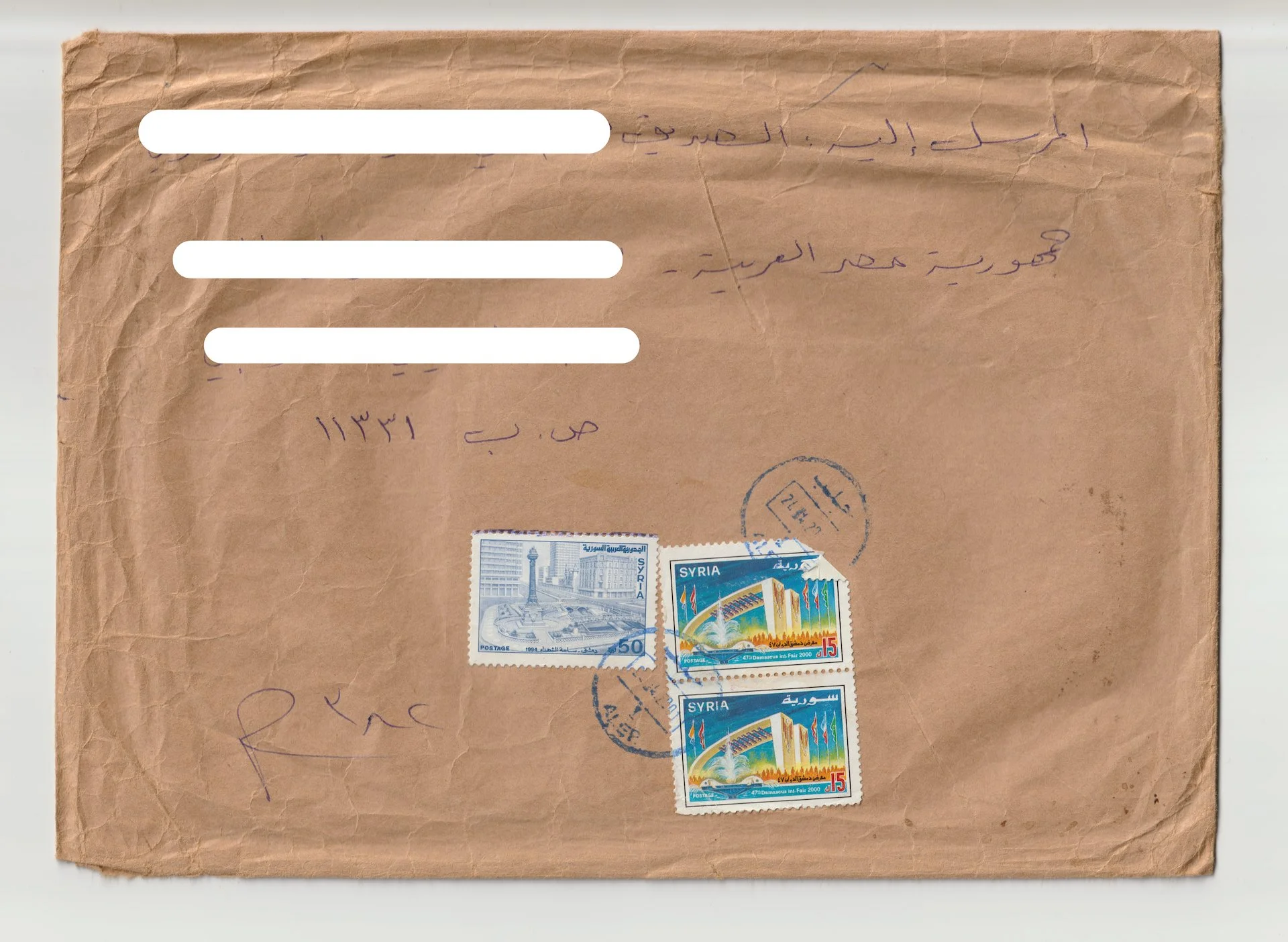 Old brown envelope with Arabic handwriting, three postage stamps from Syria, and circular postal marks.