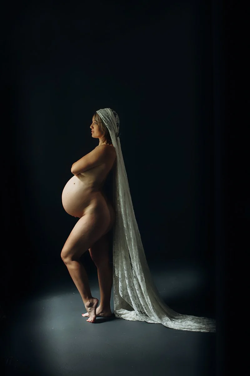 A dramatic fine art maternity boudoir portrait of a pregnant woman in profile with a flowing lace veil, photographed by Emily Scott in Beaufort, SC.